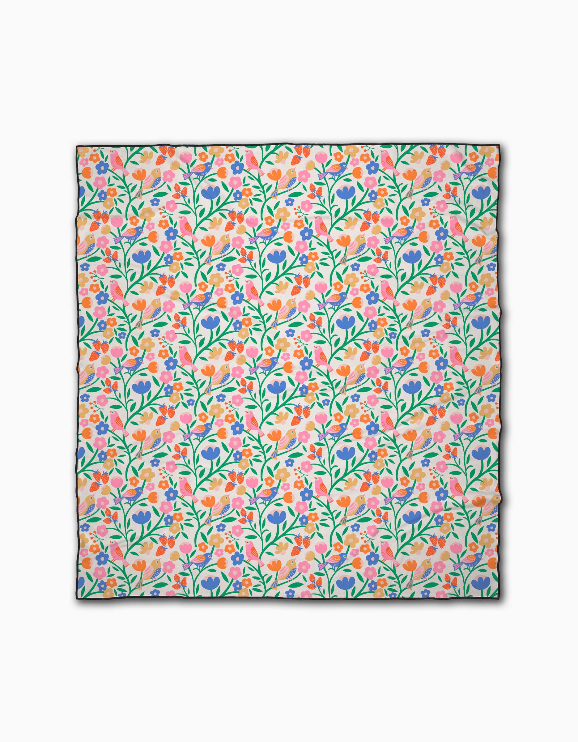 The Primrose Path beach blanket by Charlie Rowan Designs features a colorful, dense floral pattern with green stems and pink, orange, purple, and blue flowers on white. Made from recycled materials with black-edged detailing.