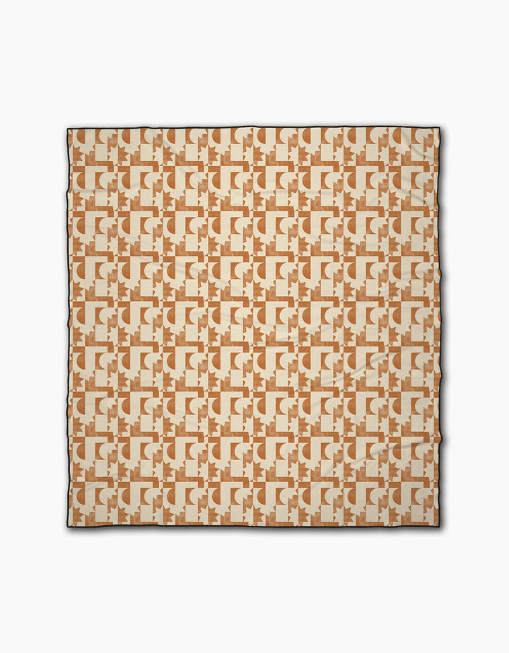 The Solar Power beach blanket by Geometry is a square design featuring interlocking abstract shapes in beige and brown on a cream background, made from quick-drying recycled materials with a slim dark border.