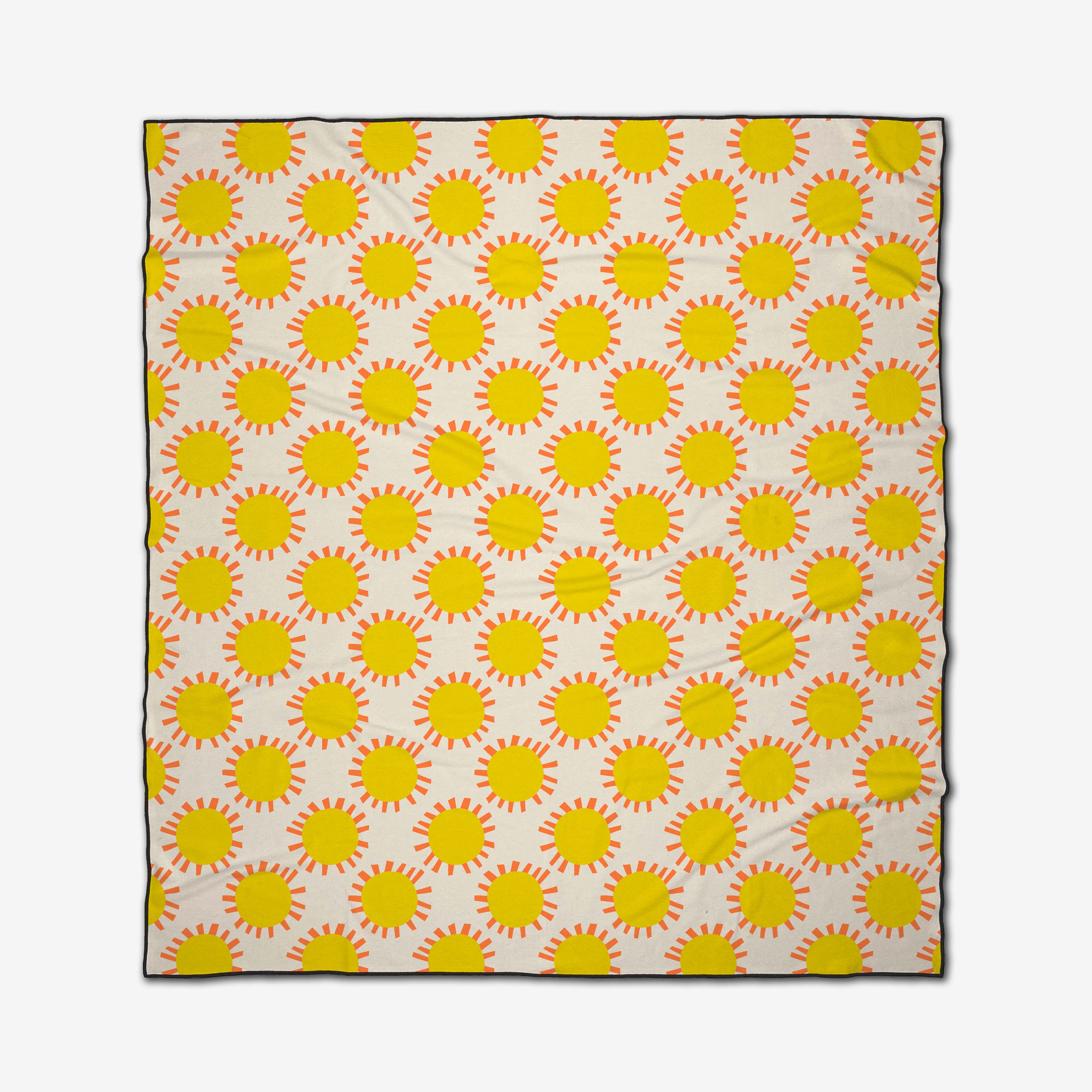 The Sunny Day rectangular beach blanket by Lizzie Clark features yellow suns with orange rays on a white background. Made from quick-drying recycled materials, it has a slightly wrinkled appearance.