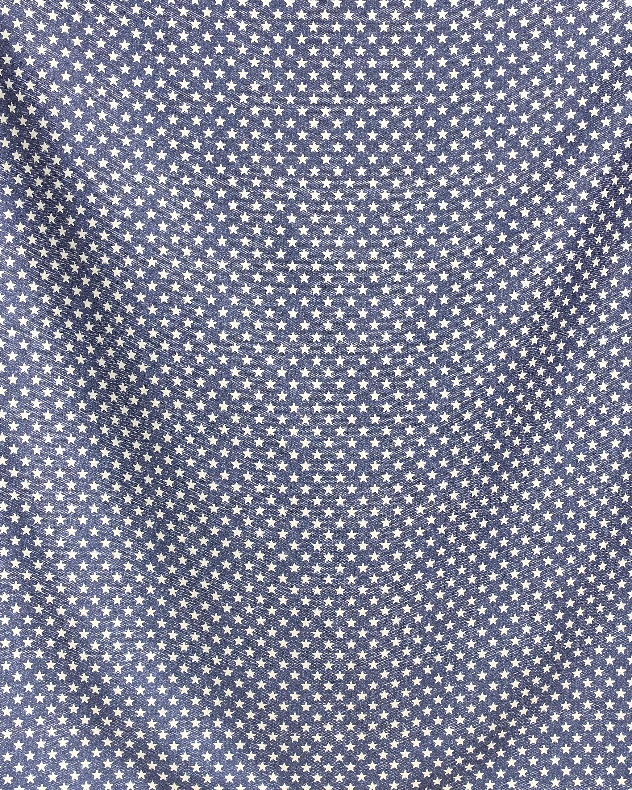 The Valor beach blanket by Geometry features quick-drying blue fabric adorned with evenly spaced white stars; its slightly wrinkled surface adds soft shadows and texture to the star pattern.