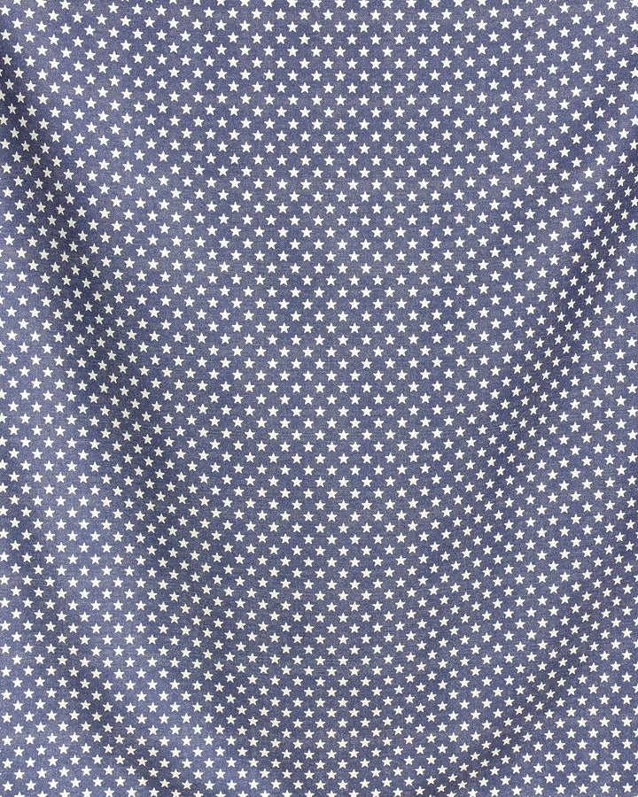 The Valor beach blanket by Geometry features quick-drying blue fabric adorned with evenly spaced white stars; its slightly wrinkled surface adds soft shadows and texture to the star pattern.