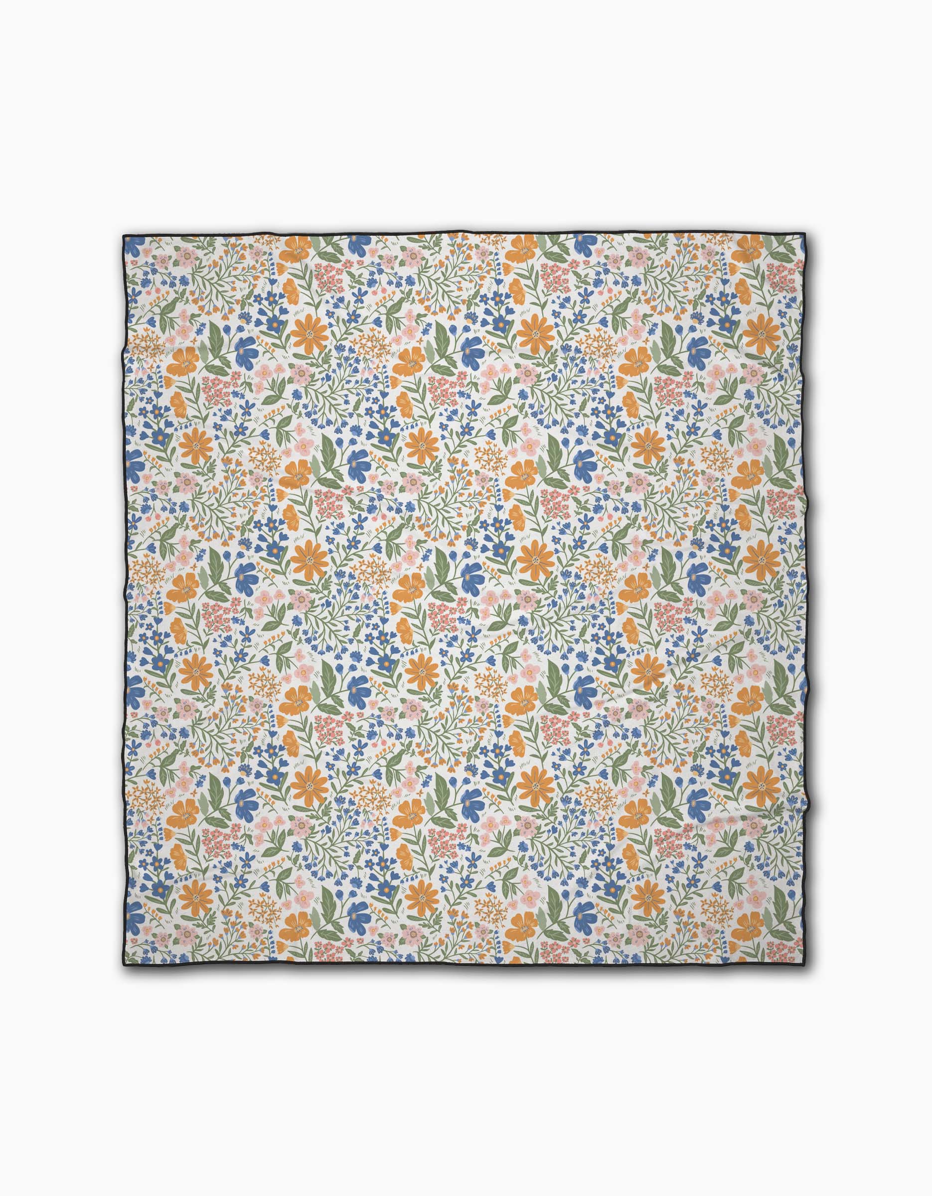 The Wildflower Vine Blush by Danelys Sidron is a square scarf with a vibrant orange, blue, and green floral print on white. Made from recycled materials, it features a thin dark border for an eco-friendly, chic finish.