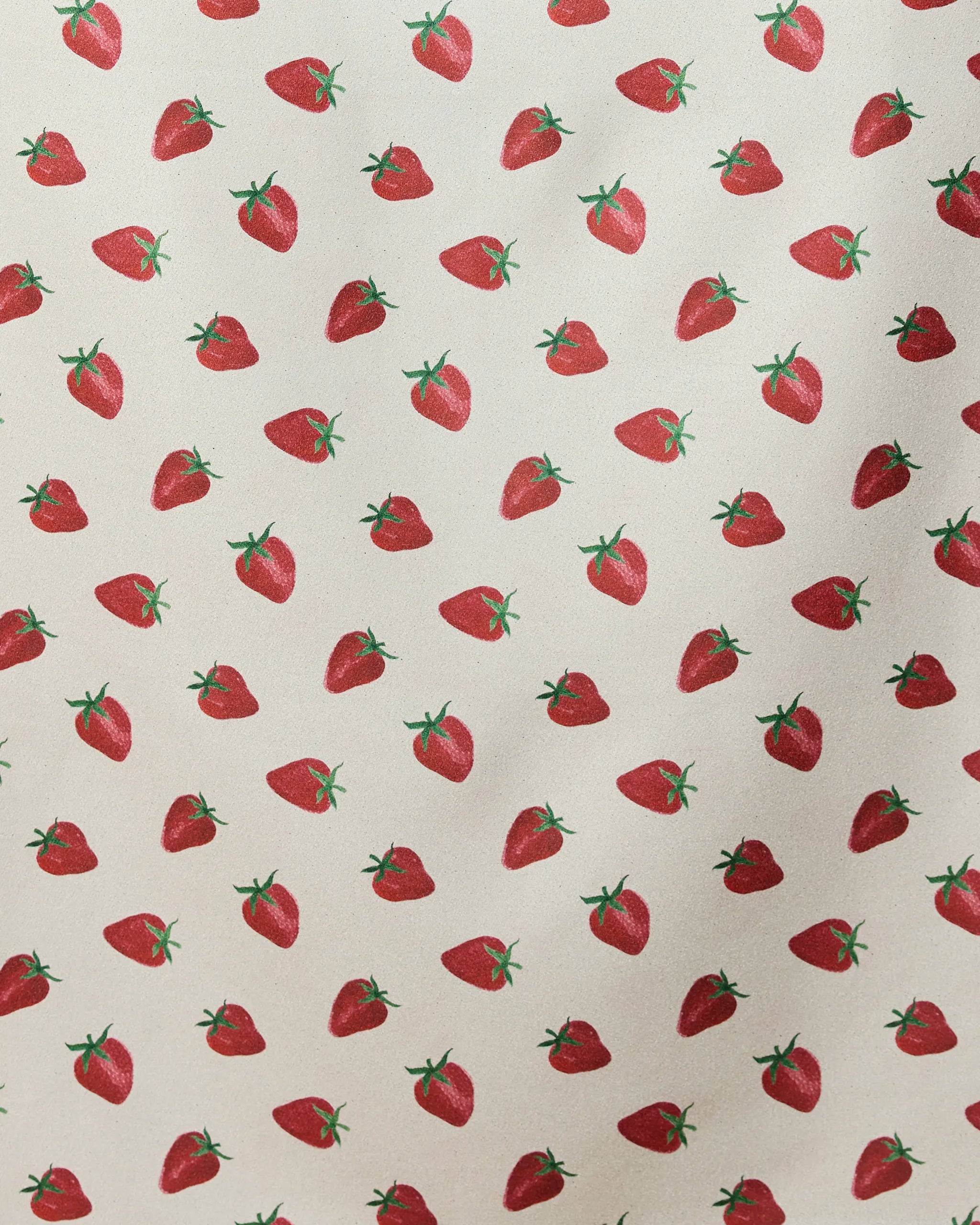 The Geometry Berry Patch micro-loop beach towel features a repeated pattern of red strawberries with green stems on light beige. Evenly spaced and oriented in different directions, this quick-drying towel is made from recycled materials.