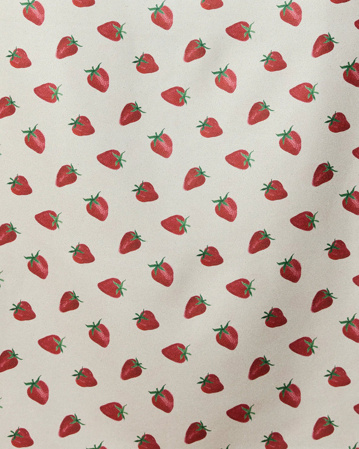 The Geometry Berry Patch micro-loop beach towel features a repeated pattern of red strawberries with green stems on light beige. Evenly spaced and oriented in different directions, this quick-drying towel is made from recycled materials.