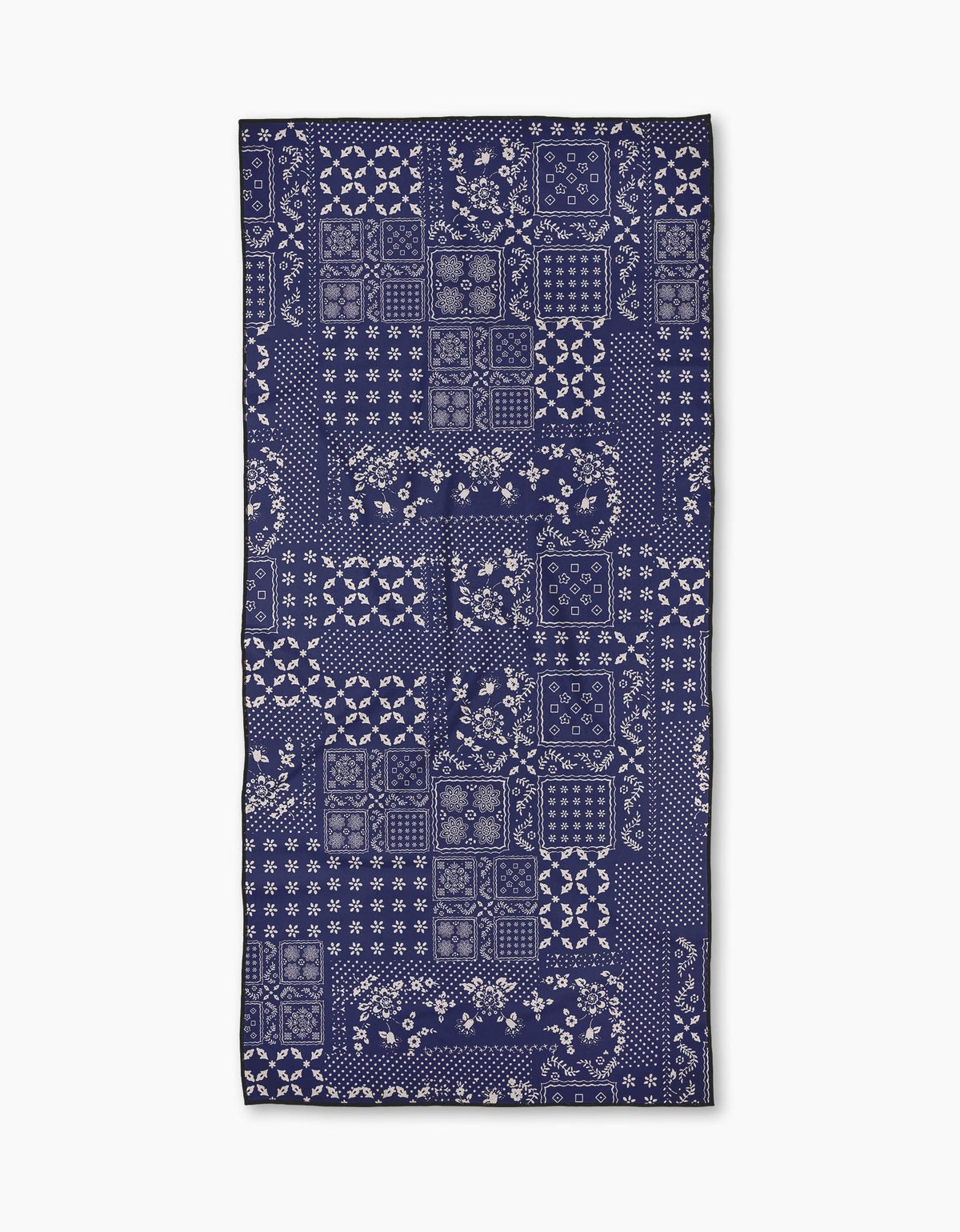 A rectangular Blossoming Bandanna Blue beach towel by Geometry, featuring a navy and white floral and geometric pattern, made from quick-drying post-consumer recycled materials, is laid flat on a white background.