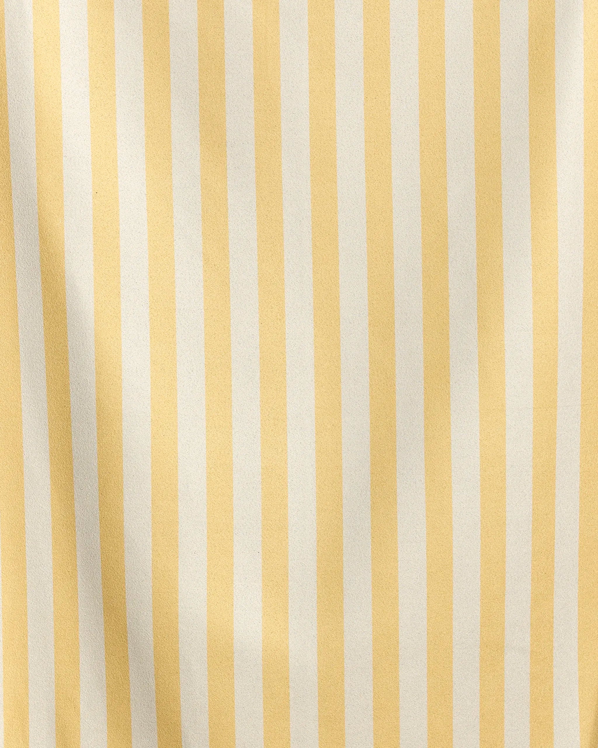 A close-up of Geometry's Cabana quick-drying fabric features vertical yellow and white stripes. The material is slightly wrinkled, creating subtle shadows along the stripes.