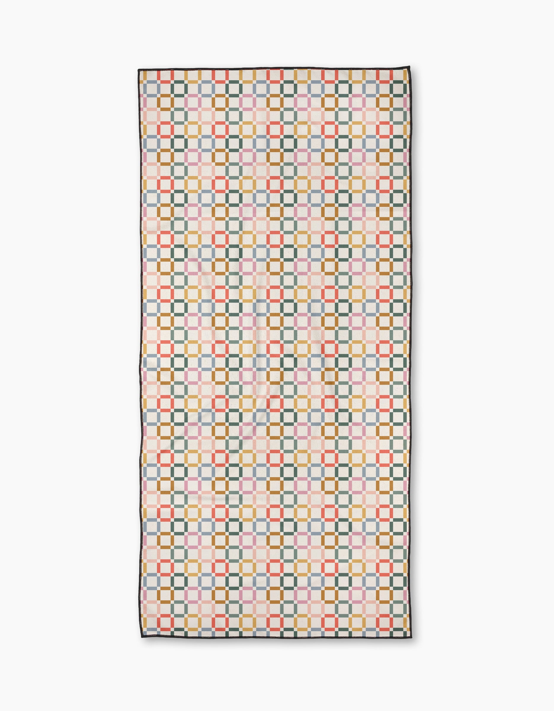 The “Crossroads” beach towel by Charlie Rowan Designs features a geometric pattern of colorful squares and circles on white, outlined in black. Made from quick-drying recycled materials, it’s finished with thin black-edged borders.