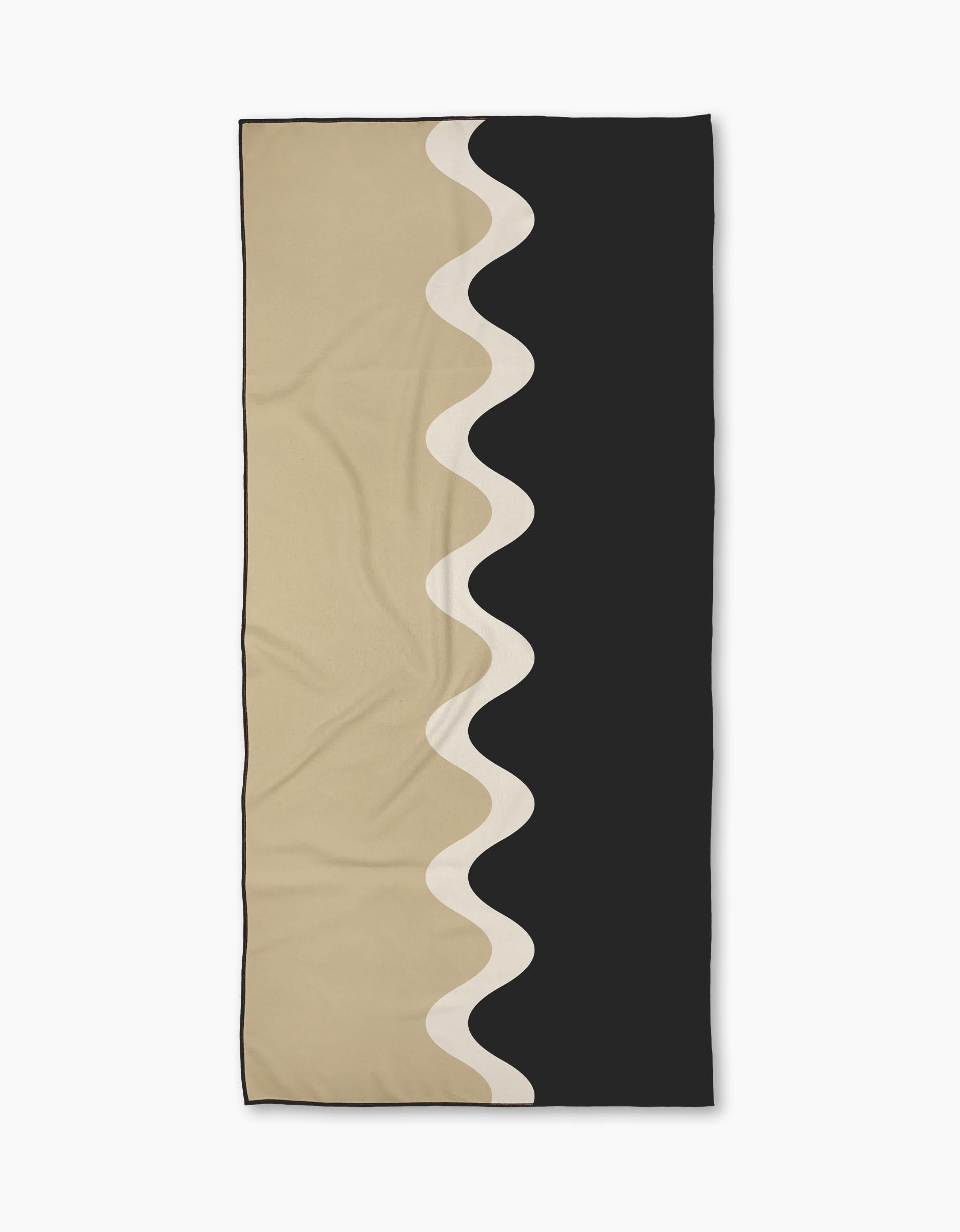 The Geometry Dune Drift Micro-loop Beach Towel features a beige left side, black right side, and a vertical white wavy line. Made from post-consumer recycled materials, its an eco-friendly, stylish, and quick-drying beach essential.