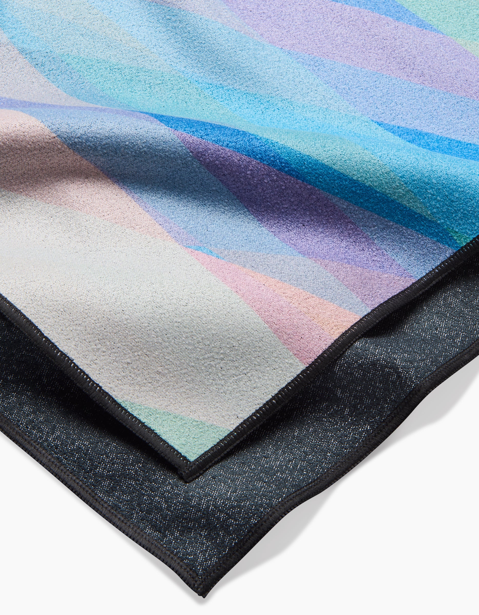 A close-up of Eventide by Rachel Parker shows pastel diagonal stripes in blue, purple, pink, and beige on textured recycled fabric above solid dark gray fabric, both finished with black stitched edges.