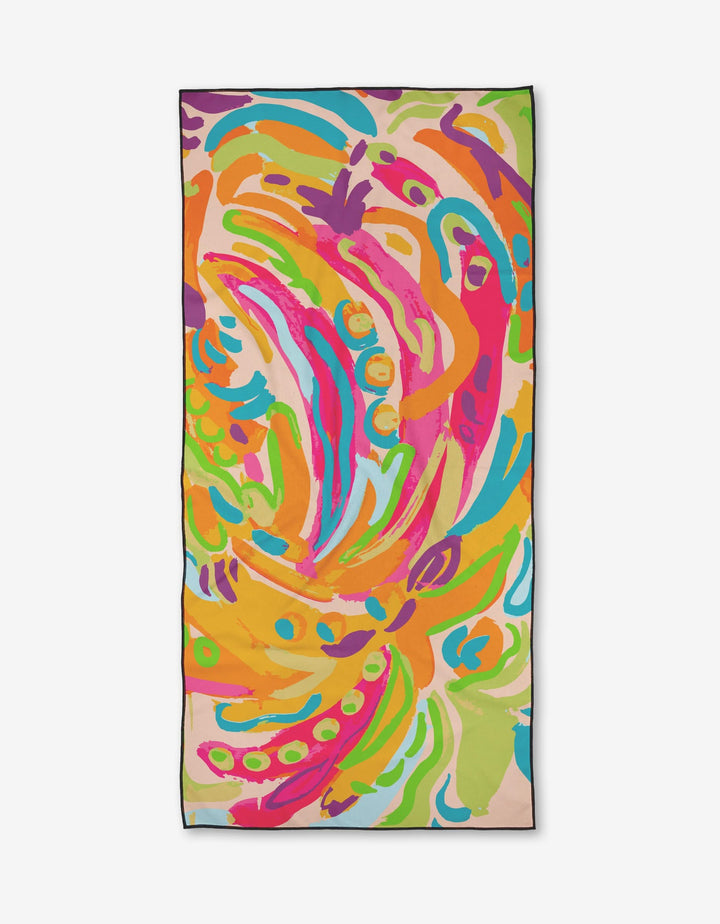 The Sareka Unique Florescence is a rectangular micro-loop beach towel with a vibrant abstract pattern in orange, pink, green, blue, and yellow brushstrokes on a light background, made from quick-drying recycled materials.