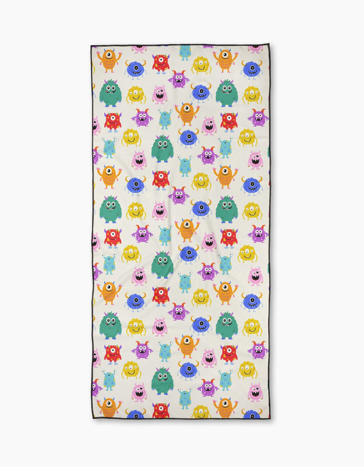 Goofy Critters by Vaishali Design Studio is a rectangular micro-loop beach towel with a playful pattern of colorful cartoon monsters—pink, yellow, green, blue, and orange—of various shapes and expressions on a white background.