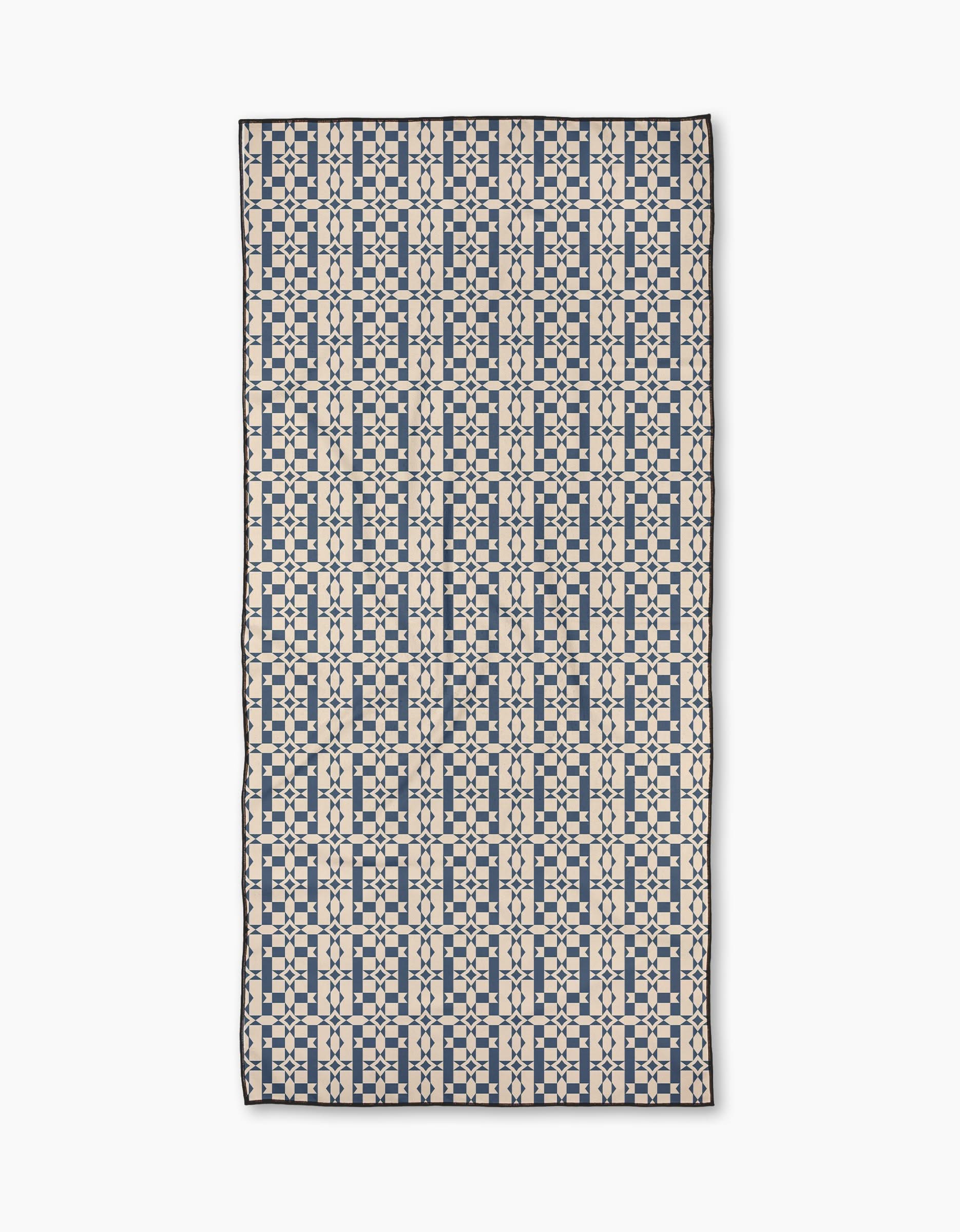 The Geometry Intermission Blue Micro-loop Beach Towel features a grid-like geometric pattern of navy squares and lines on cream, made from quick-drying, post-consumer recycled materials.