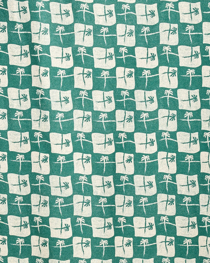 The La Brisa Green towel by Geometry features cream squares with palm tree designs on green micro-loop fabric. Made from recycled materials and quick-drying, it adds a tropical geometric vibe to your beach days.