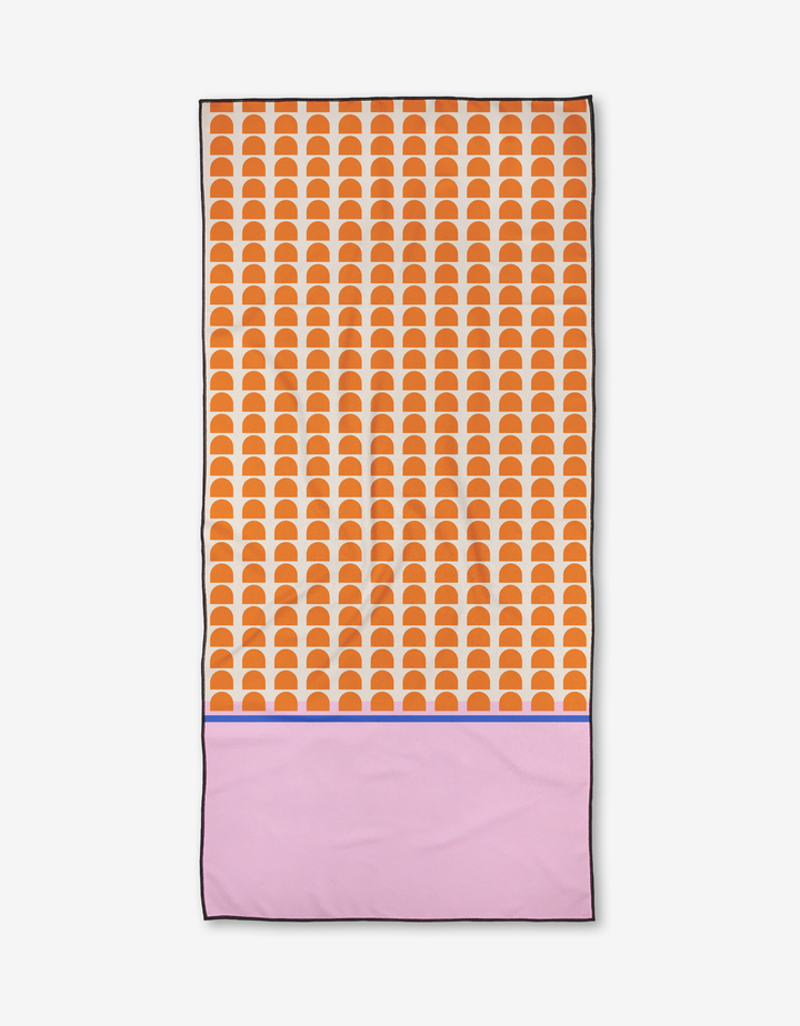 The Pink Illusion towel by Happy Hemera features an orange scallop pattern on the top two-thirds, a solid light pink section below, and a blue dividing line. Quick-drying and made from recycled materials.