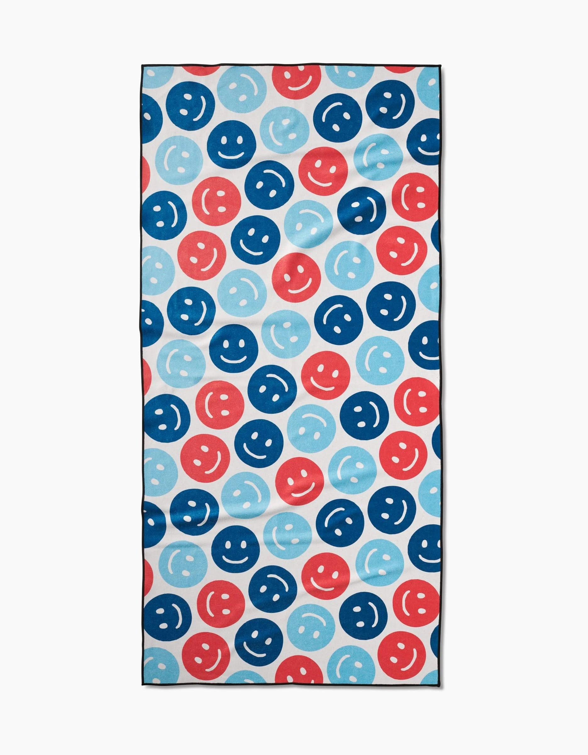 The “Smiley Face July” beach towel by Hufton Studio features a playful pattern of red, blue, and light blue smiley faces on white. Made from quick-drying recycled materials, it’s ideal for pool or beach days.