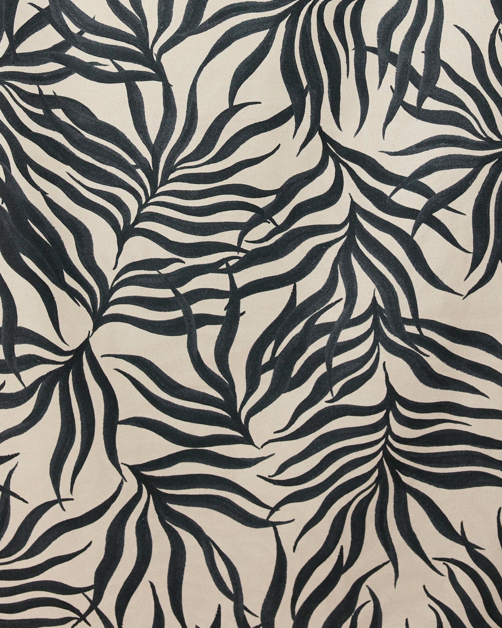 The Geometry Solar Flare beach towel features bold, abstract black palm leaf patterns on a light beige background with flowing lines. Made from recycled materials, this quick-drying towel adds a tropical flair to your beach days.