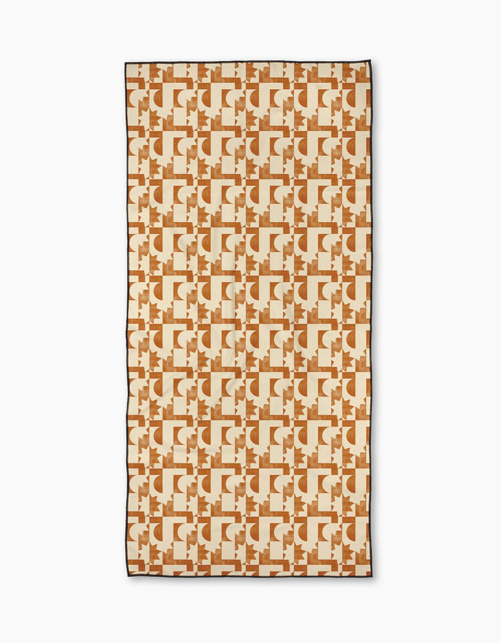 The Geometry Solar Power Micro-loop Beach Towel features a geometric pattern in tan and brown with interlocking designs on a cream background, made from quick-drying recycled materials.