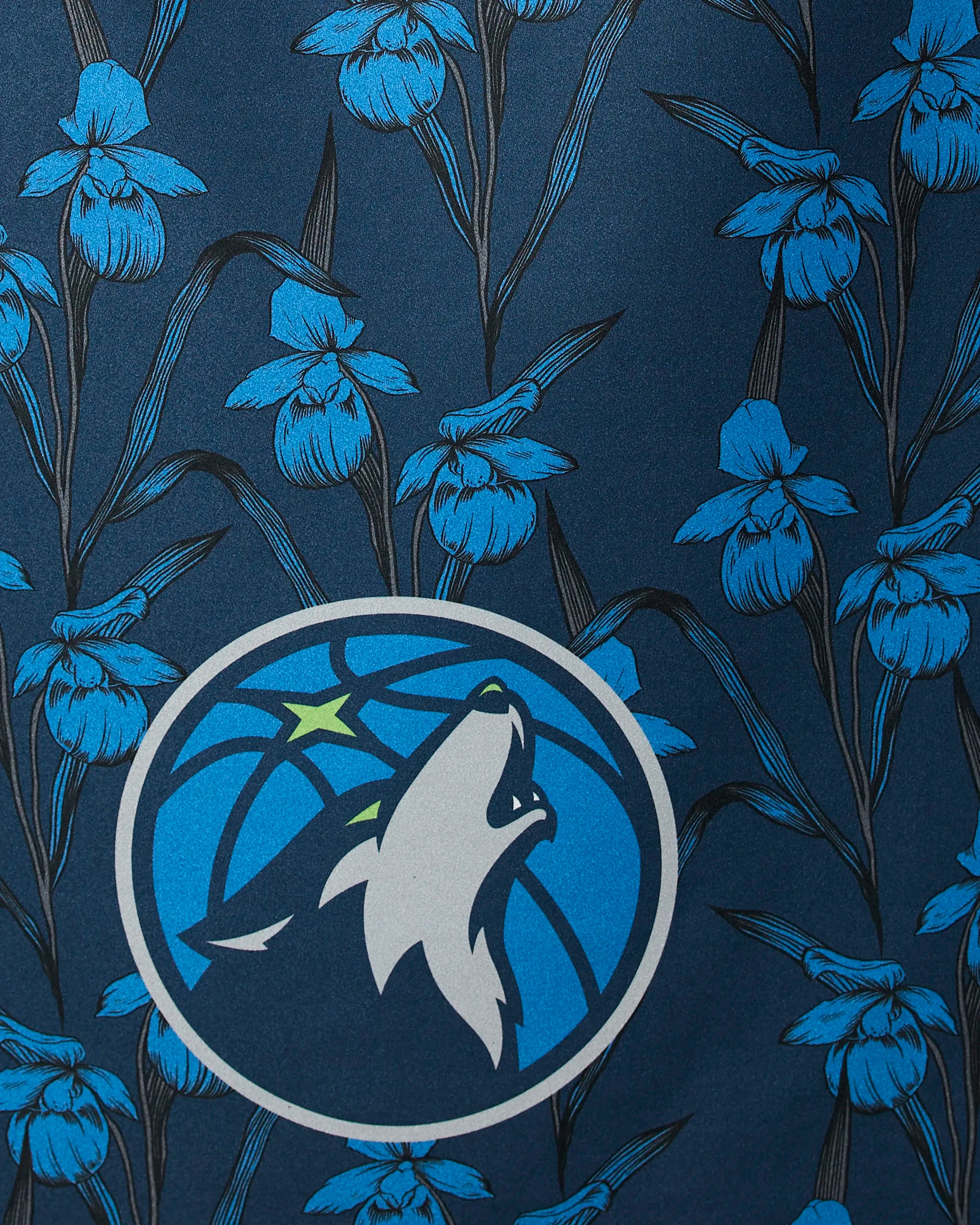 A close-up of the Timberwolves Floral by Geometry, showing blue iris flowers and dark stems with the Minnesota Timberwolves logo at the center.