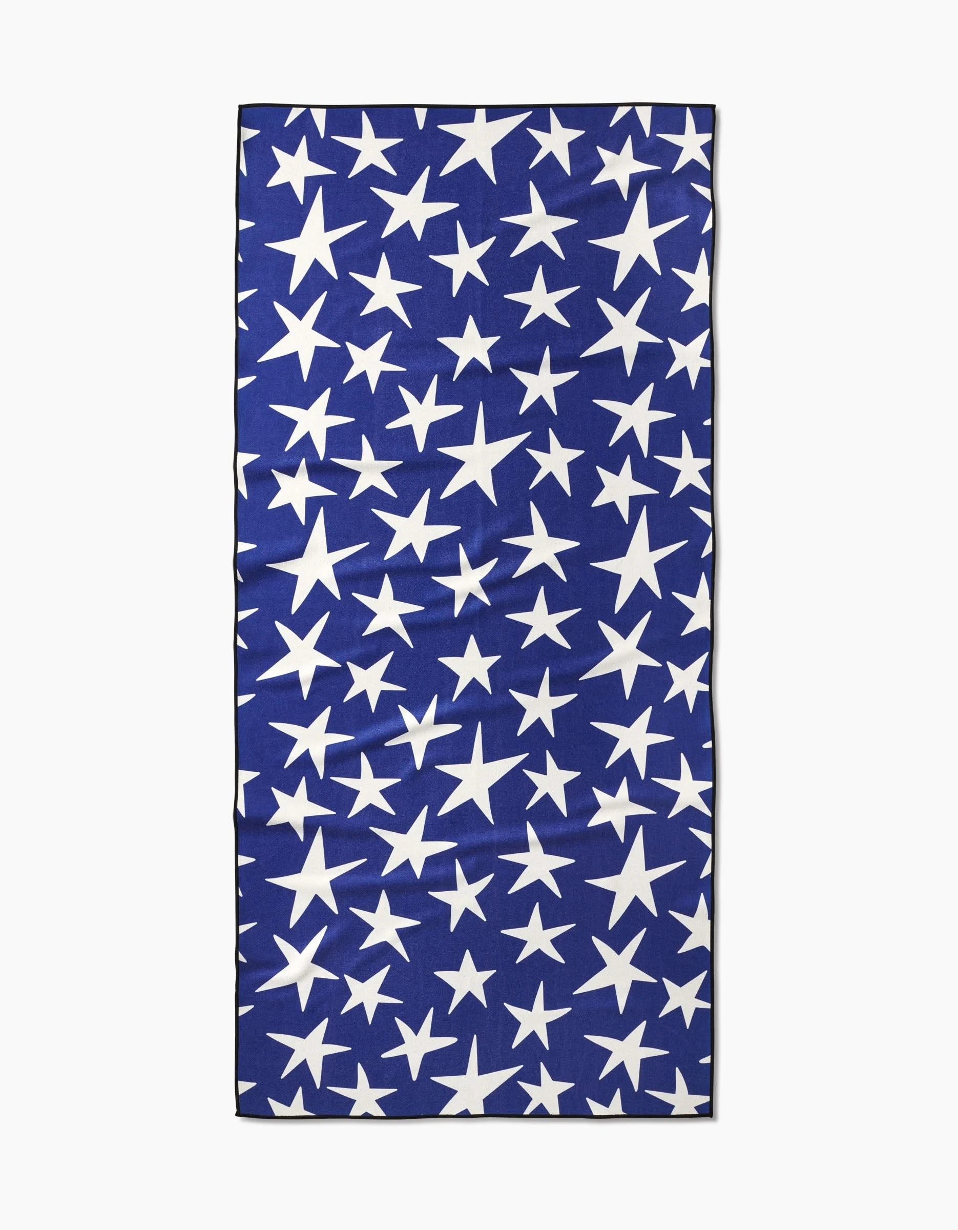 The Mindfulnice USA Stars Beach Towel is a rectangular blue towel with scattered white stars in various sizes. Made from recycled materials, this quick-drying Micro-loop towel is shown laid flat with slight wrinkles.