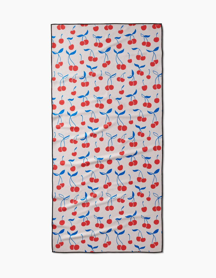 The Kayla Ann Very Cherry Micro-loop Beach Towel features red cherries and blue leaves on light beige, bordered in black. Compact, quick-drying, and crafted from recycled materials.