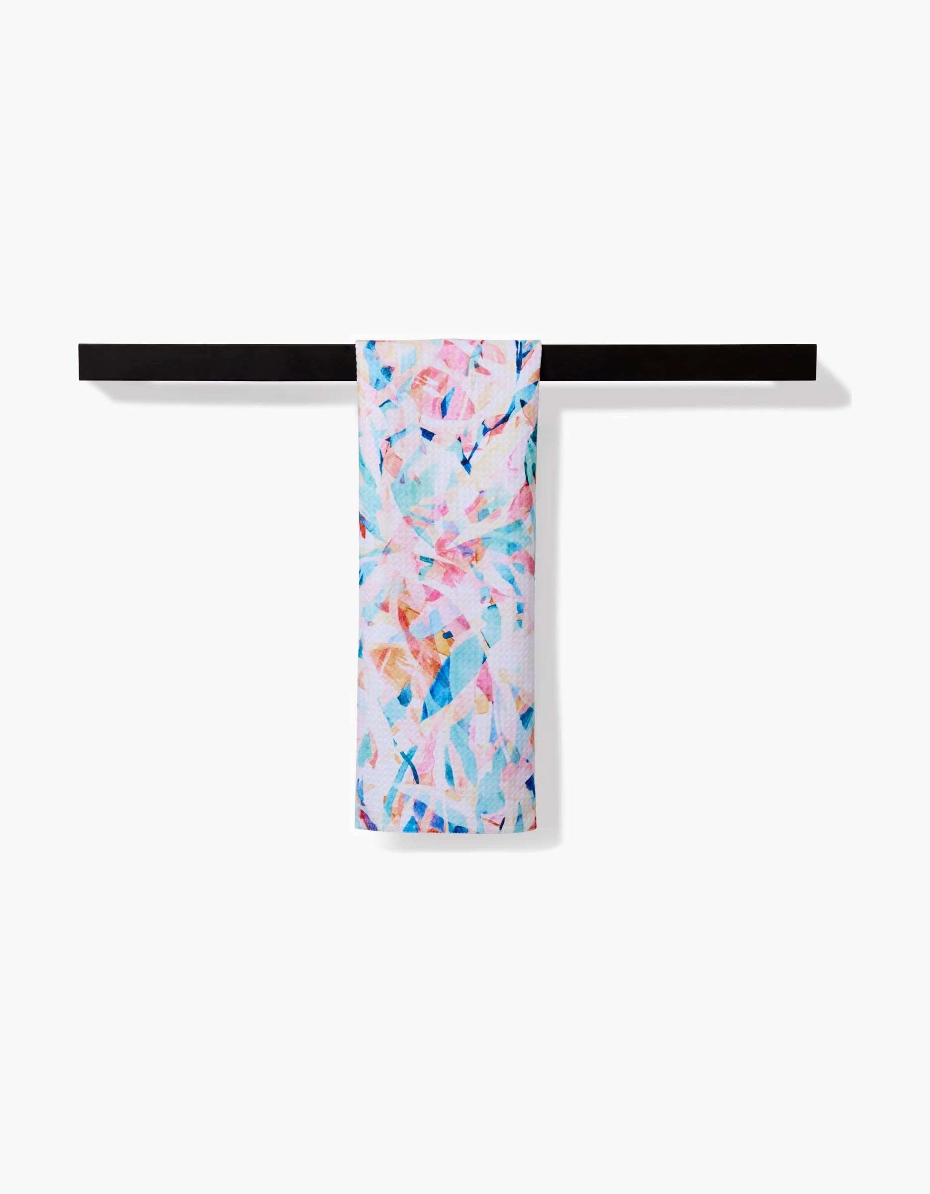 The Abstract Jungle bar towel by Rachel Parker, featuring a vibrant pink, blue, and orange geometric design, hangs on a black towel bar. Made from soft Geoweave fabric for superior absorbency.