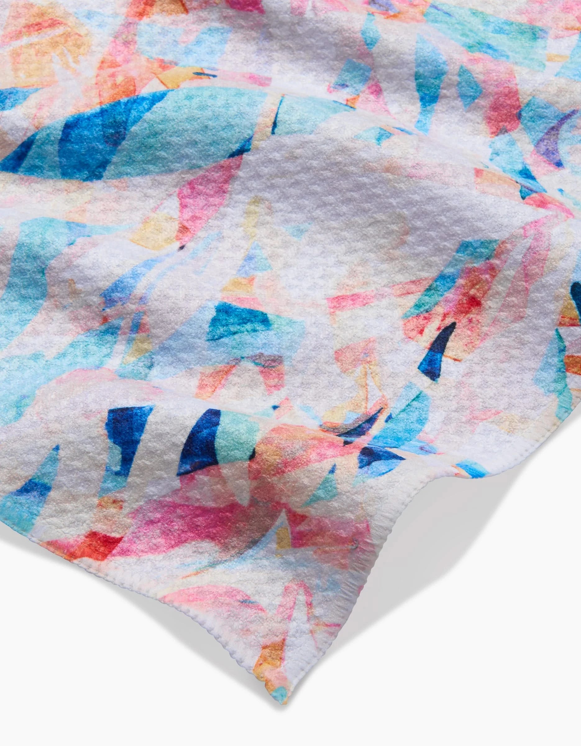 A close-up of the Rachel Parker Abstract Jungle bar towel shows its textured white Geoweave fabric with pink, blue, and orange overlapping brushstrokes and a wavy scalloped edge.