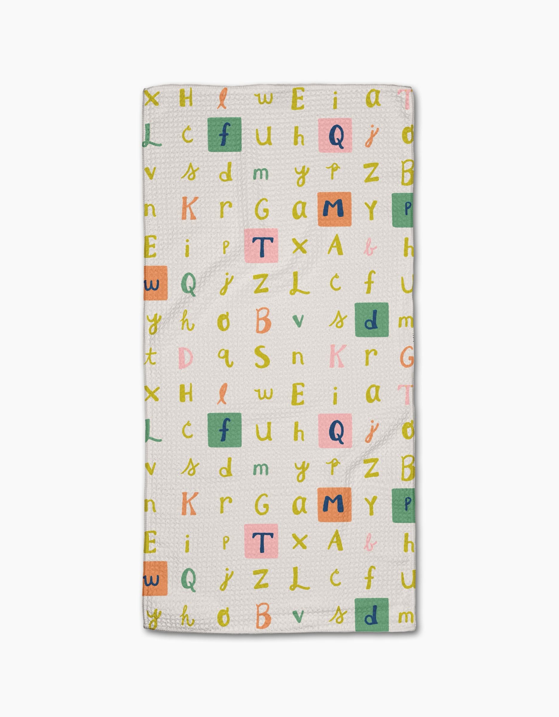 The Alphabet Light Bar Towel by Amy MacCready is rectangular, white, made from recycled materials, and features a scattered pattern of colorful uppercase and lowercase letters—yellow, pink, green, and orange—with some highlighted in colored squares.