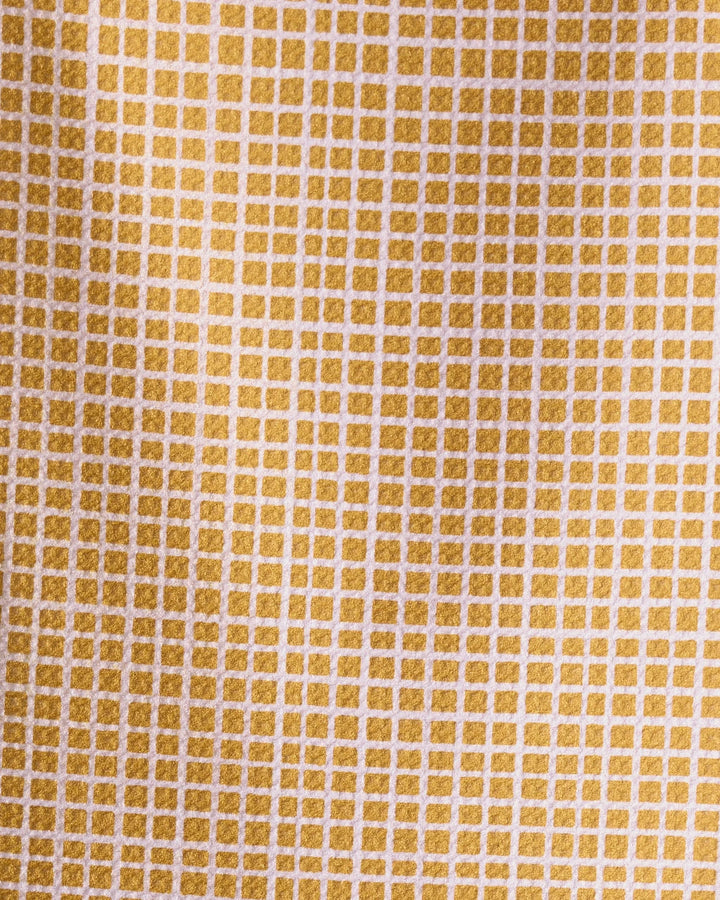 Close-up of the Amberline towel by Geometry, featuring an ultra-absorbent texture and a yellow and white grid pattern with small, evenly spaced squares. Lighting highlights its detailed design and depth.