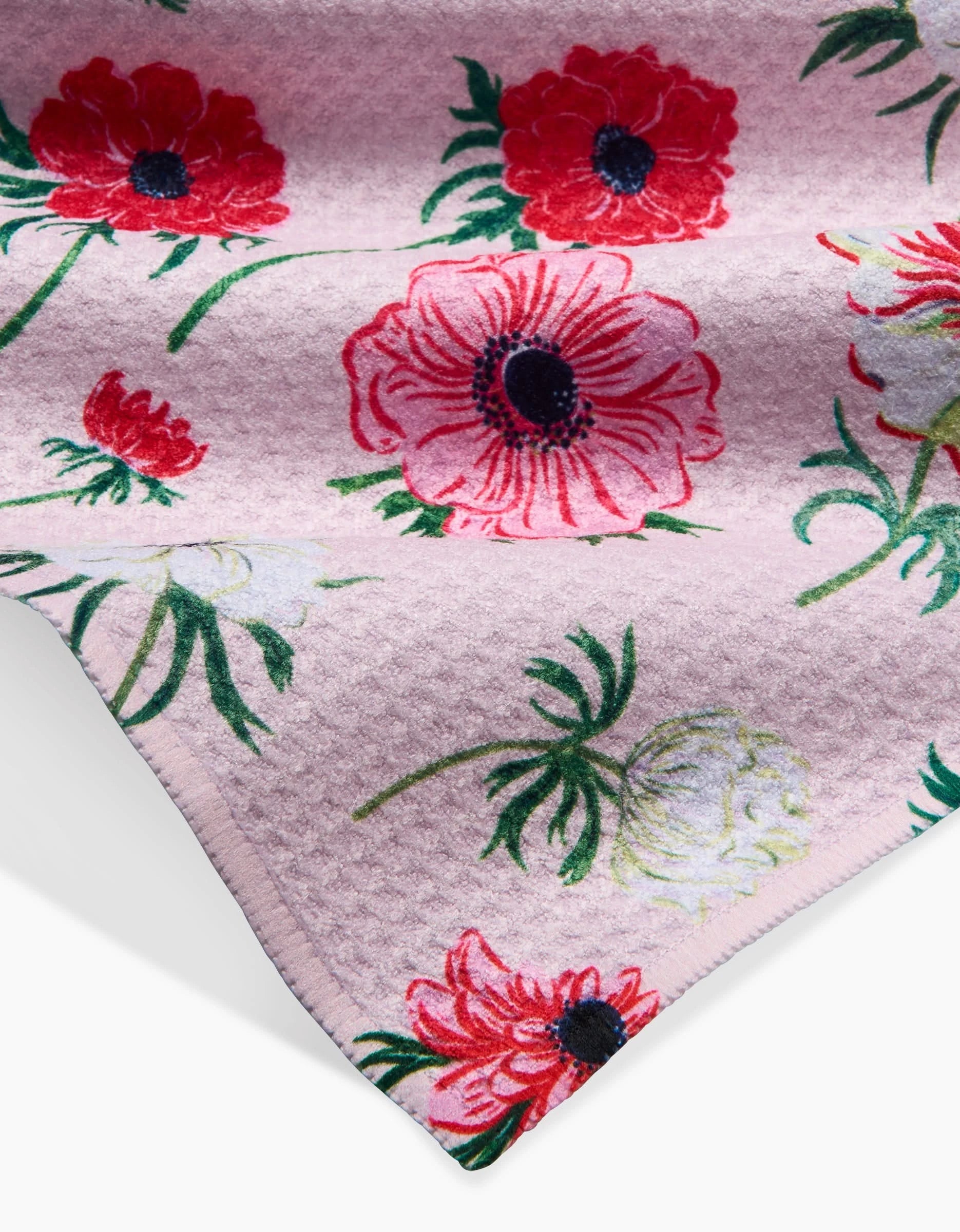 A close-up of Linda Foxs Anemone Garden Flowers shows soft pink Geoweave fabric with a quilted texture and a floral pattern of large red, pink, and white flowers with green stems and leaves.