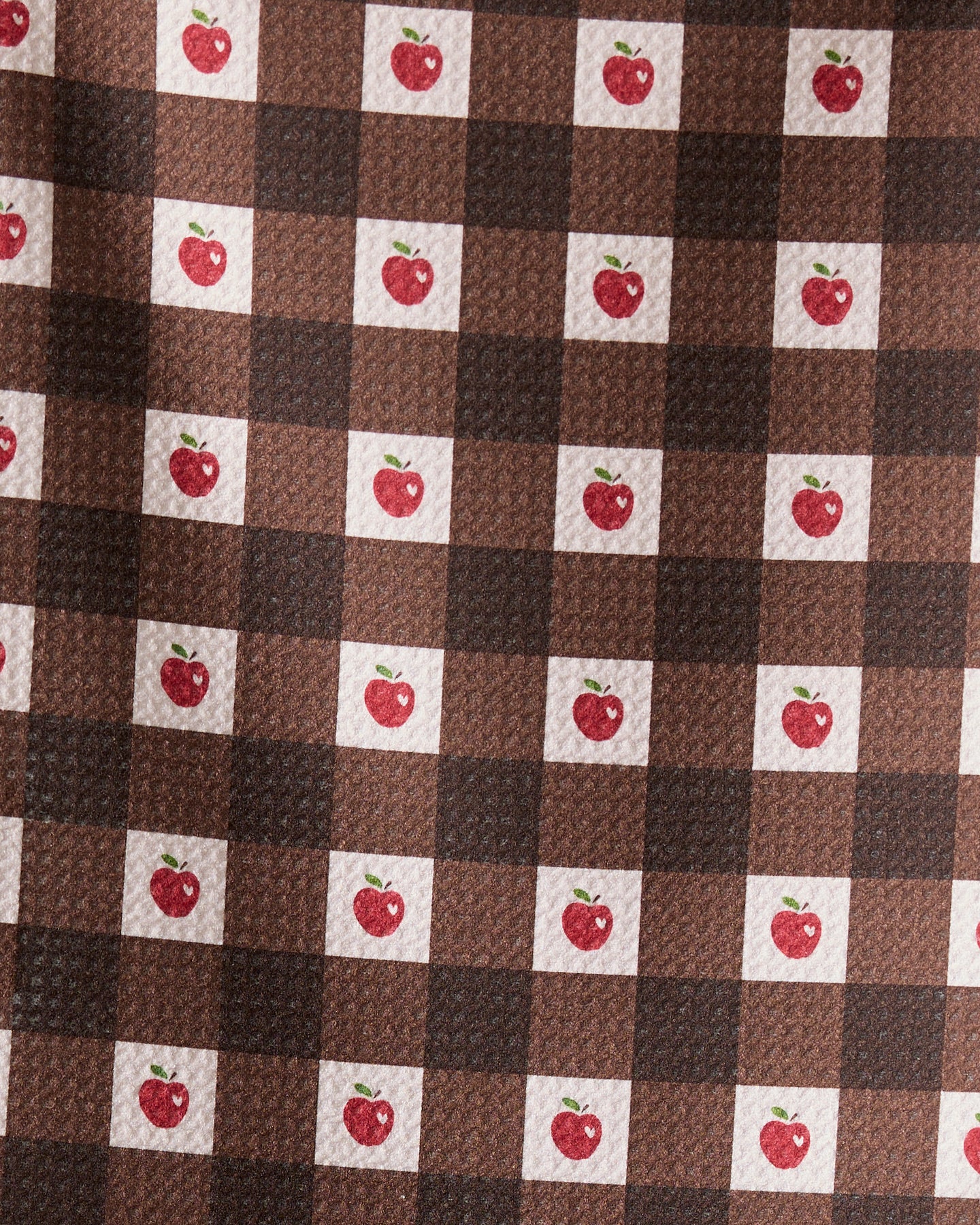 The Geometry Apple Picnic bar towel features a brown and dark brown checkered pattern with small red apples and green leaves in some white squares. Ultra-absorbent and textured, it combines style with function.