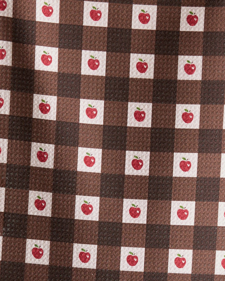 The Geometry Apple Picnic bar towel features a brown and dark brown checkered pattern with small red apples and green leaves in some white squares. Ultra-absorbent and textured, it combines style with function.