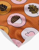 The Apples Acorns towel by Megan Roy is brown, quick-drying, and soft with a repeating pattern of pink and yellow circles featuring acorns, leaves, and heart illustrations.