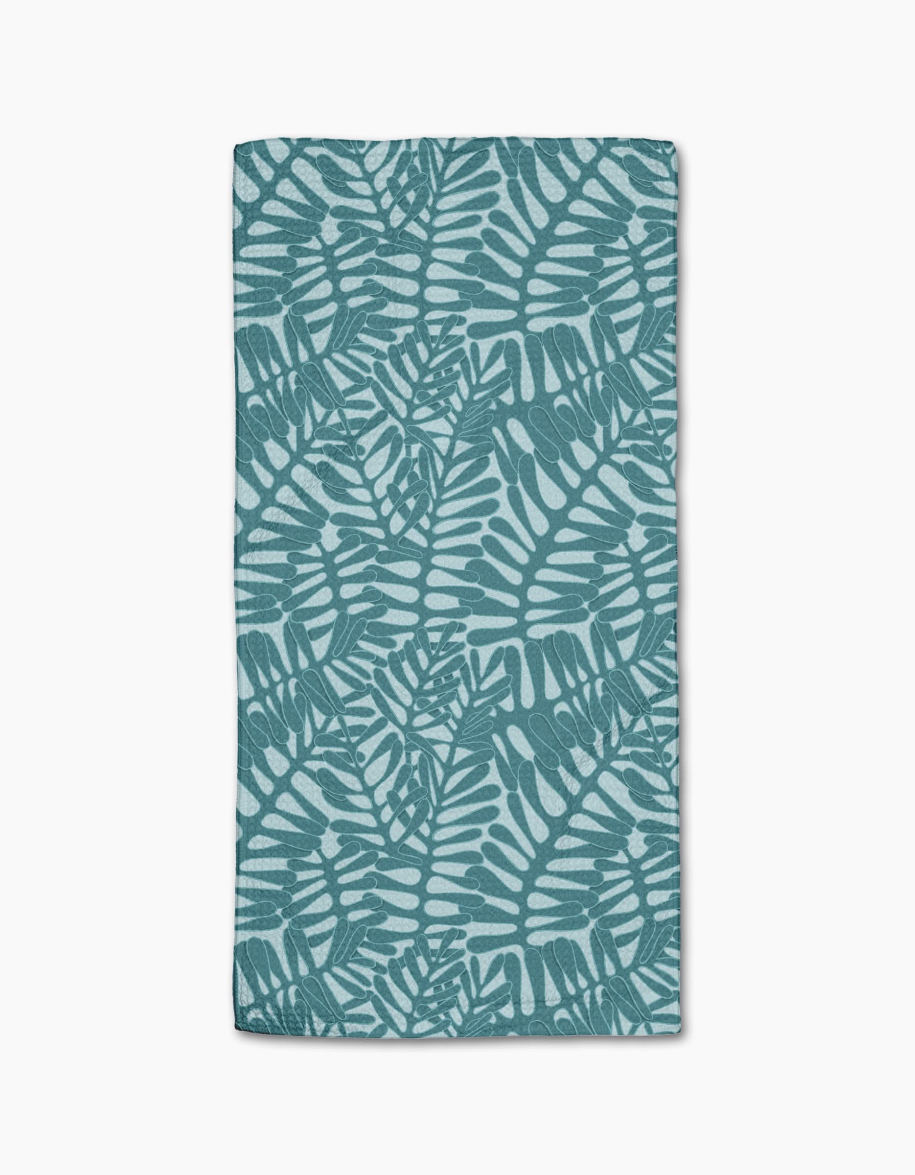 The Aqua Modern Palm towel by Katie OShea is rectangular and ultra-absorbent, showcasing a teal palm leaf pattern on a light blue background with overlapping tropical leaves in a repeating design.