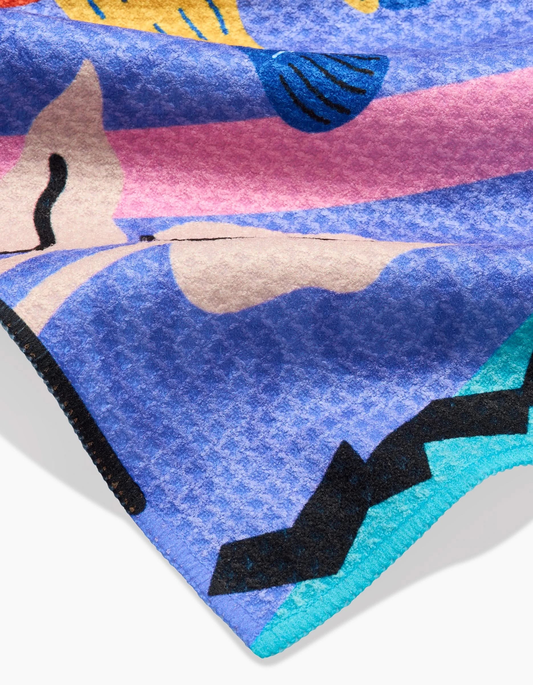 A close-up of Camila Leãos Ariranha bar towel showcases its colorful Geoweave fabric with abstract shapes in blue, pink, turquoise, beige, black, and yellow. Ultra-absorbent with a soft, textured surface and a slightly folded edge.