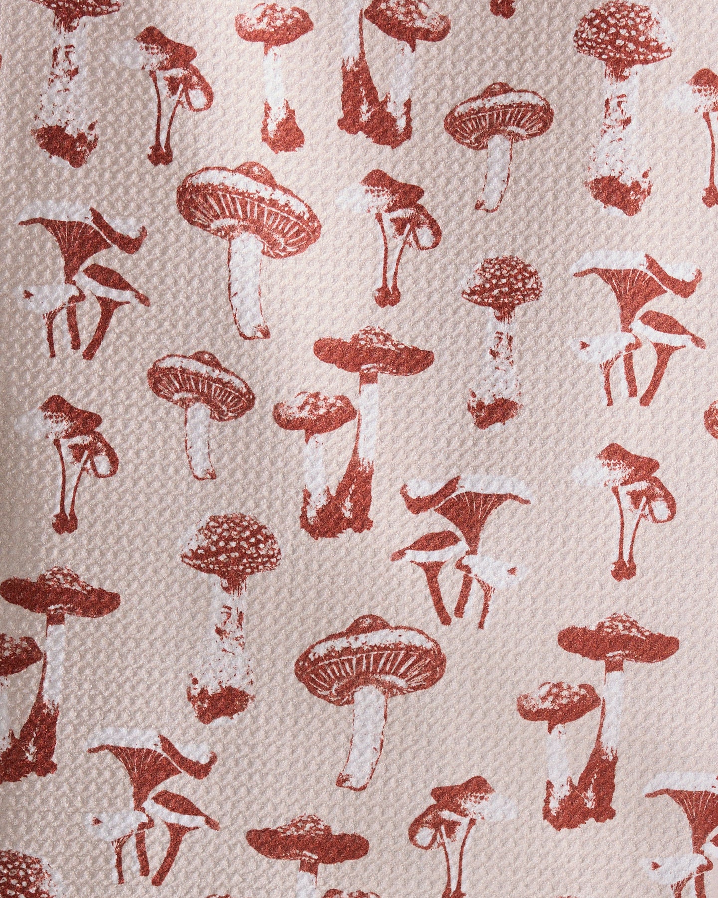 The Autumn Mushrooms towel by Geometry features a repeating pattern of brown mushrooms in various shapes and sizes on a light beige background—perfect as an ultra-absorbent or recycled kitchen towel.