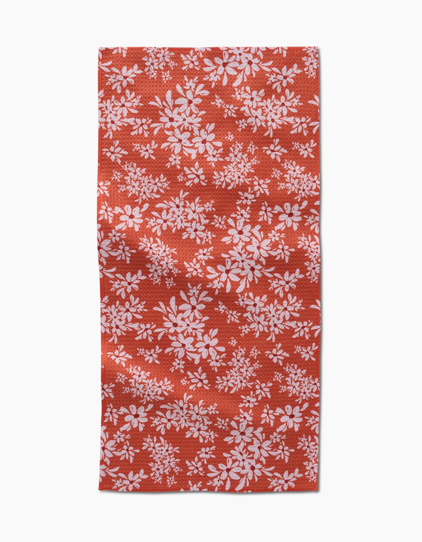 The Autumn Reverie by Ashley Celena is a red rectangular towel with a white floral pattern of scattered leaves and flowers. The ultra-absorbent fabric looks slightly wrinkled and is shown against a white background.