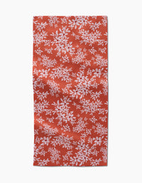 The Autumn Reverie by Ashley Celena is a red rectangular towel with a white floral pattern of scattered leaves and flowers. The ultra-absorbent fabric looks slightly wrinkled and is shown against a white background.