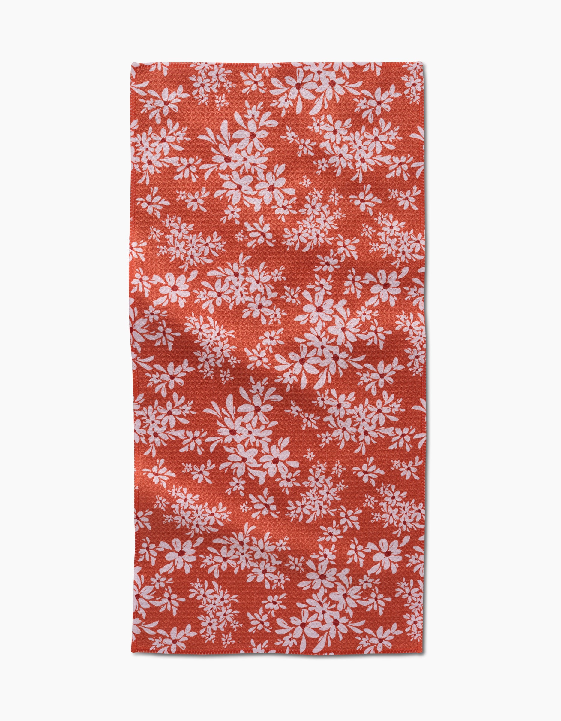 The Autumn Reverie by Ashley Celena is a red rectangular towel with a white floral pattern of scattered leaves and flowers. The ultra-absorbent fabric looks slightly wrinkled and is shown against a white background.