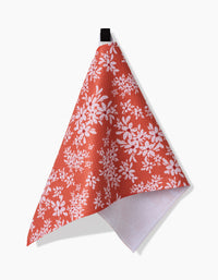 The Ashley Celena Autumn Reverie towel, featuring a red color with a white floral pattern, hangs from a black loop. Its triangular fold reveals the white textured underside against a plain white background.