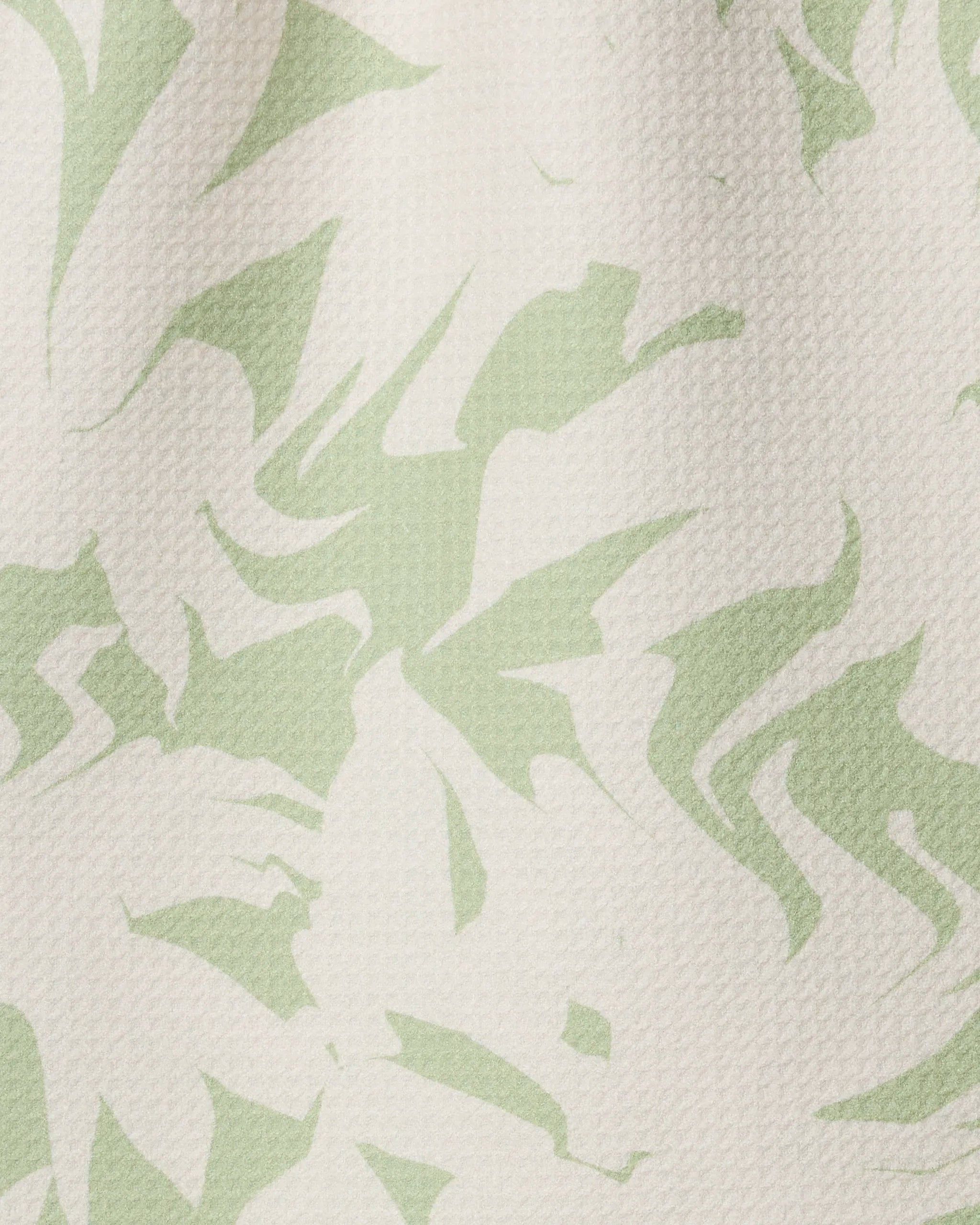 The Geometry Baysage kitchen towel features a textured recycled fabric with an abstract light green and off-white leaf-inspired pattern of swirling and jagged shapes.