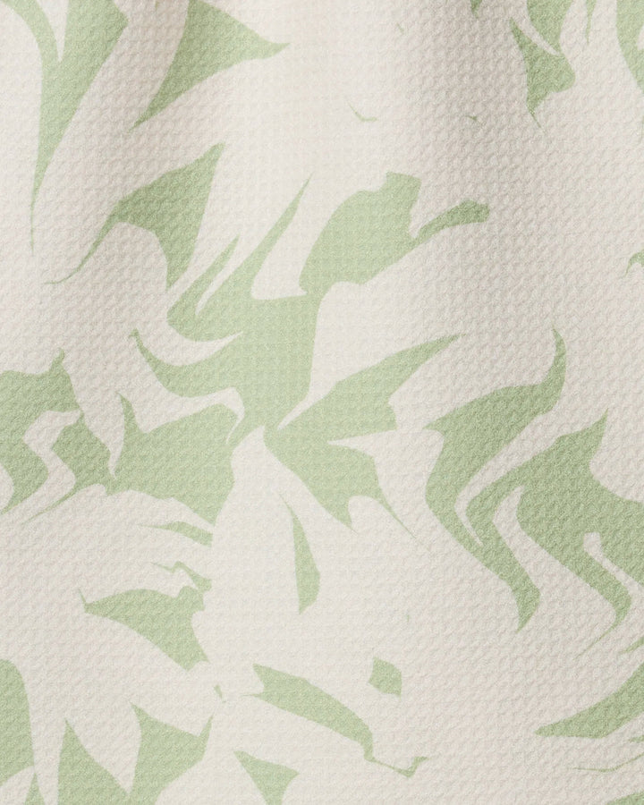 The Geometry Baysage kitchen towel features a textured recycled fabric with an abstract light green and off-white leaf-inspired pattern of swirling and jagged shapes.