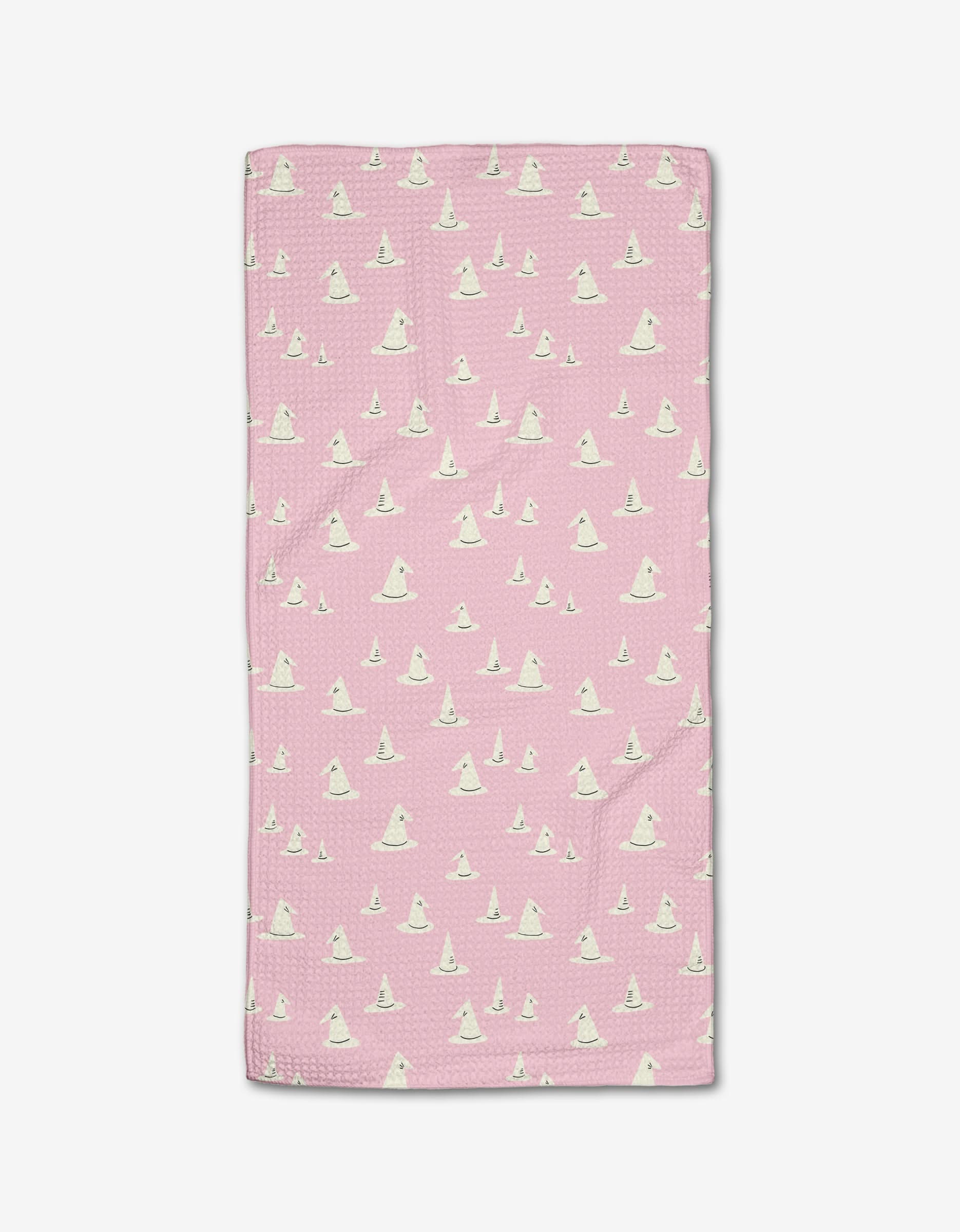 The Belladonna towel by Amy MacCready is a pink rectangular Geoweave towel featuring a repeating pattern of white ghosts with black eyes, evenly scattered across the surface and shown laid flat on a white background.