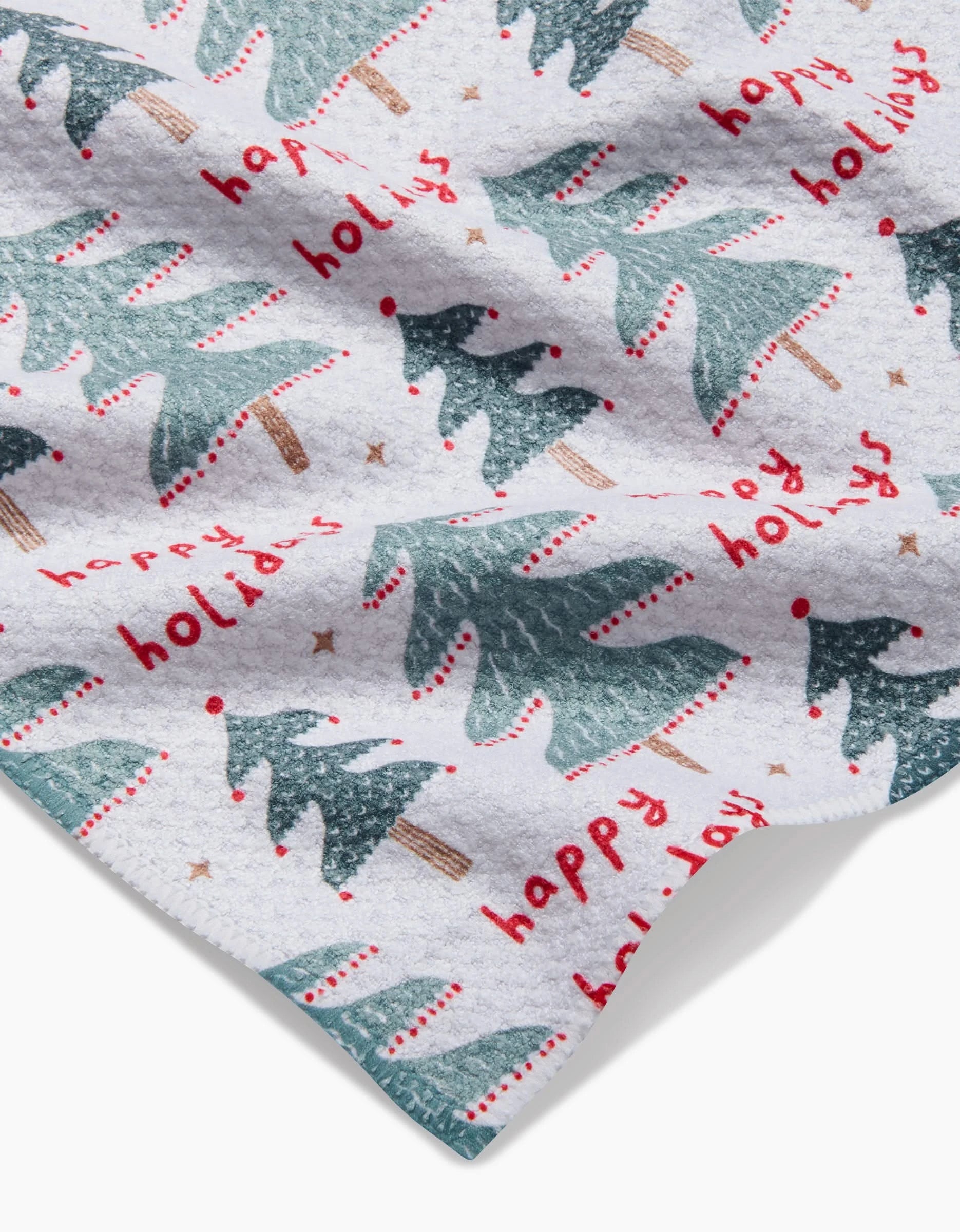 The Roxy Marj Berry Happy Holidays bar towel features green Christmas trees and red happy holidays text on a white, ultra-absorbent fabric—combining festive style and function.
