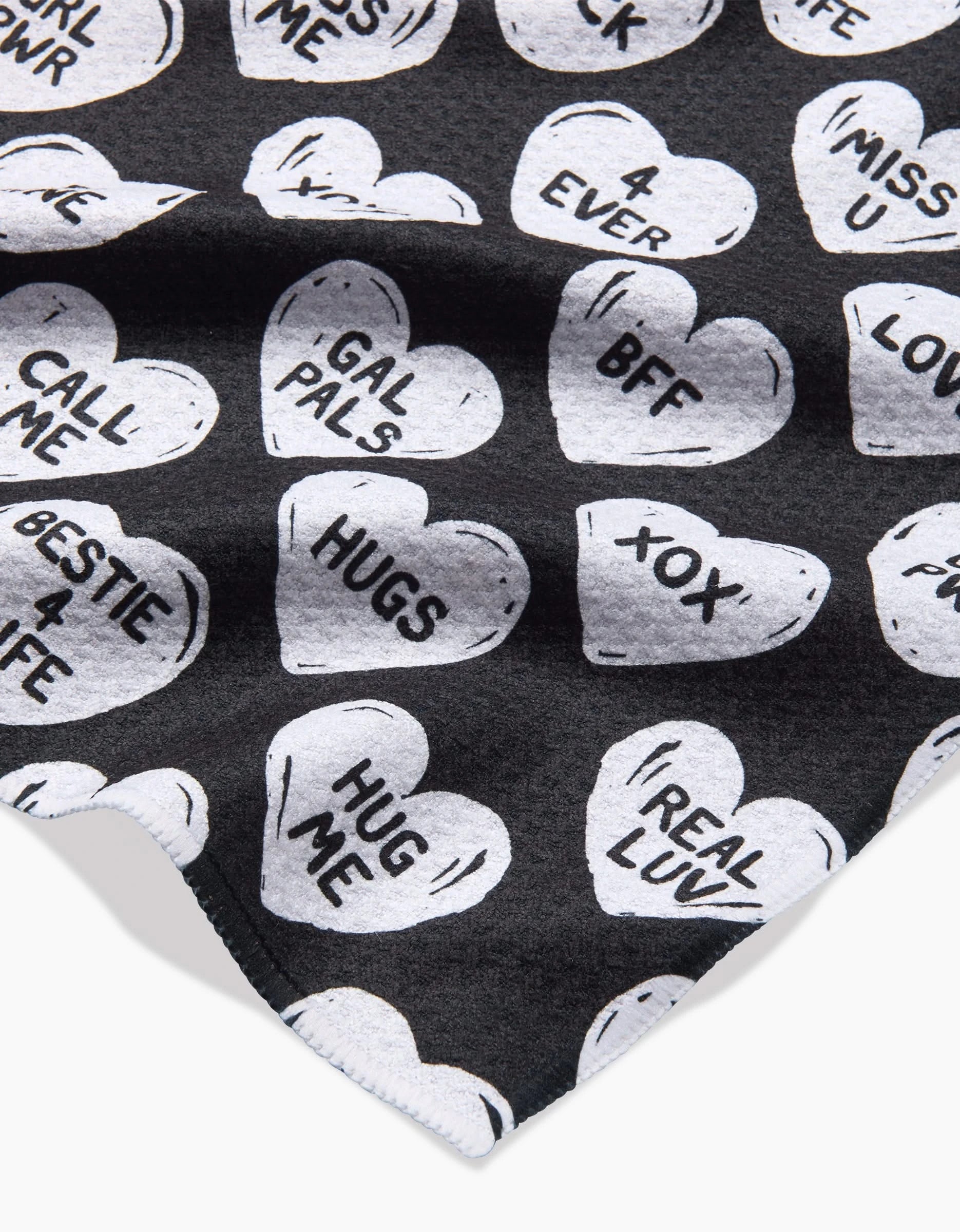 Hufton Studio’s BFF Candy Hearts is a black recycled fabric printed with white hearts. Each heart displays phrases like HUGS, BFF, REAL LUV, CALL ME, 4 EVER, and GAL PALS in bold black lettering.