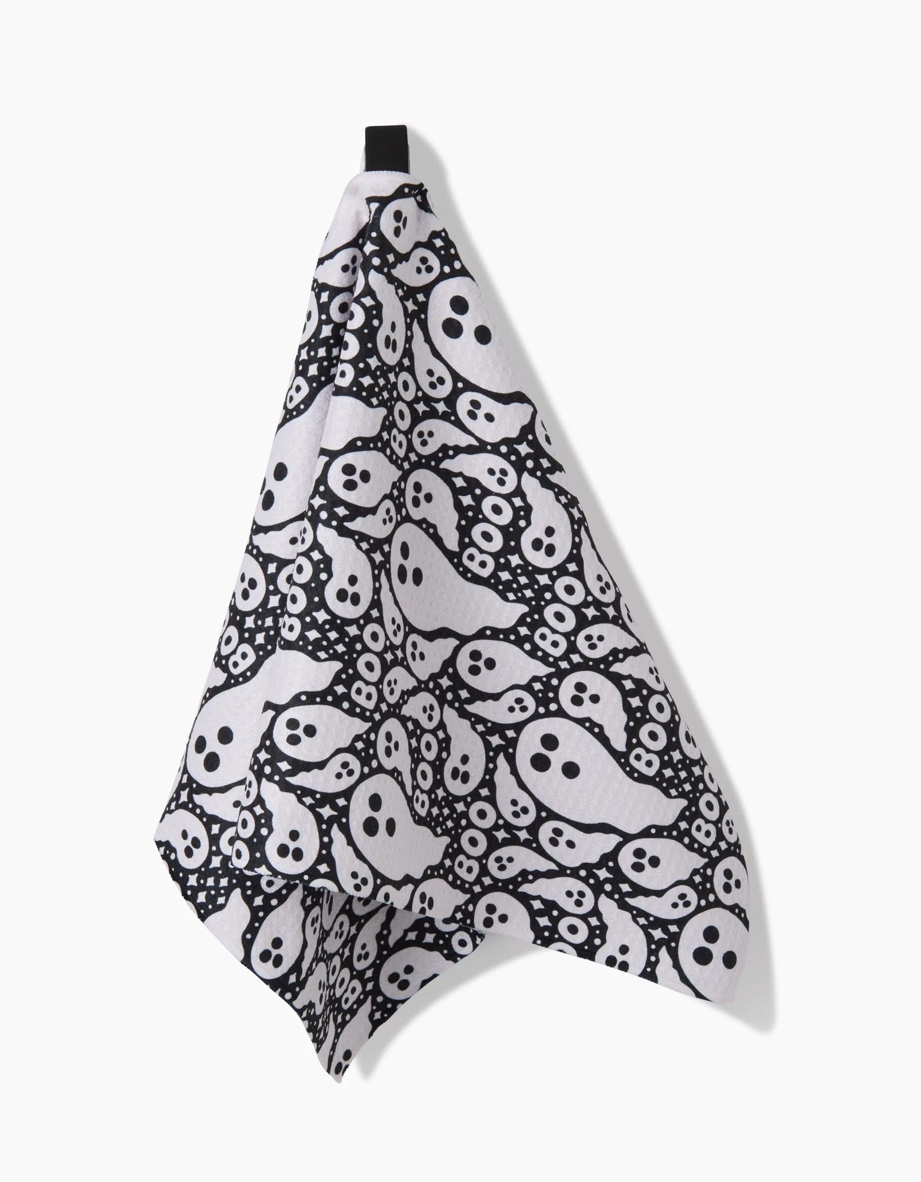 The Rosa Kichline Boo Ghosts kitchen towel, ultra-absorbent and white, hangs on a hook, covered in black-and-white cartoon ghost faces and eyes.