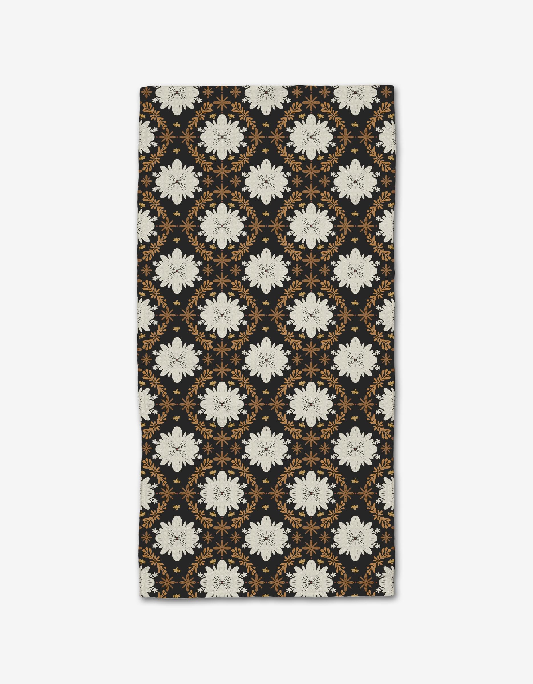 The Botanical Mosaic bar towel by Danelys Sidron features eco-friendly geoweave fabric with a balanced design of white floral motifs and orange geometric accents on a black background.