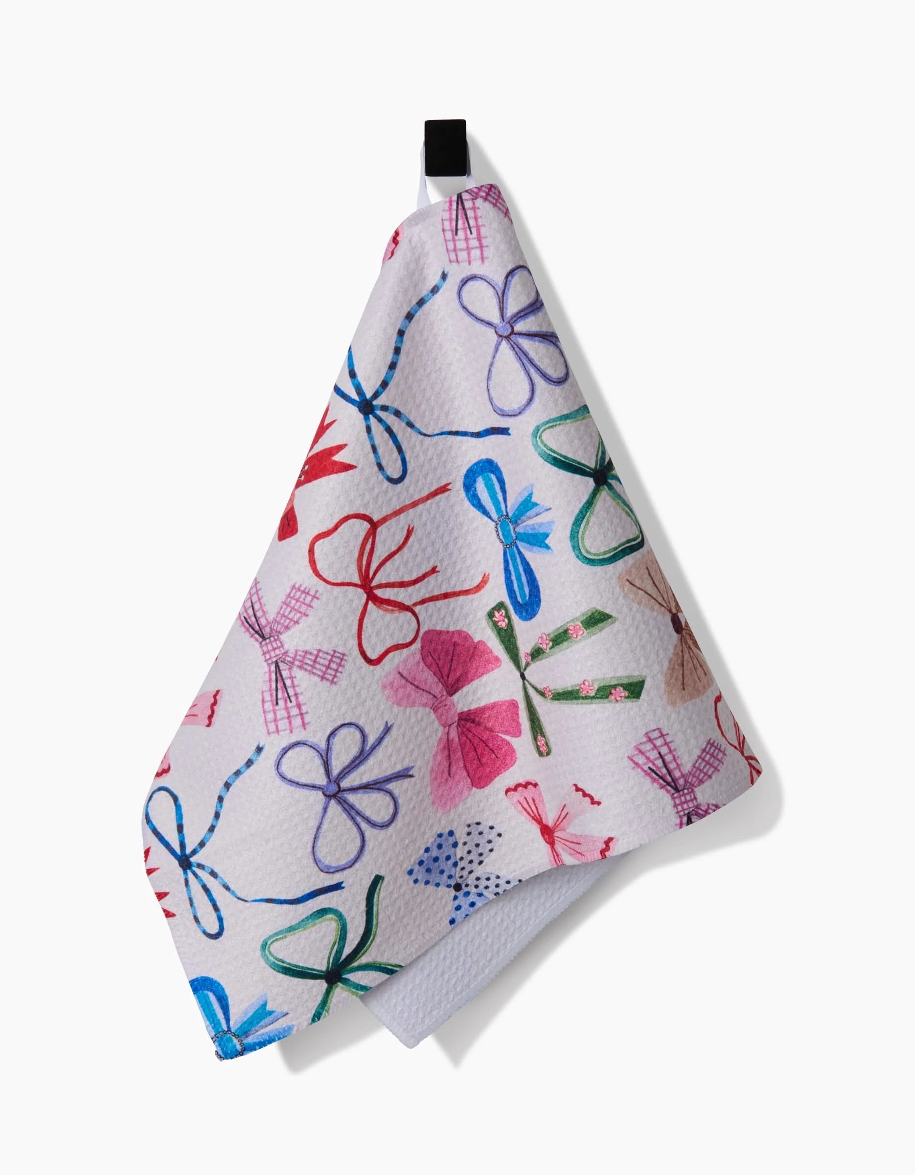 The Bows towel by Daria Solak is a white, ultra-absorbent textured towel with a black hanging loop, featuring a vibrant pattern of bows in red, blue, green, and purple in various designs.