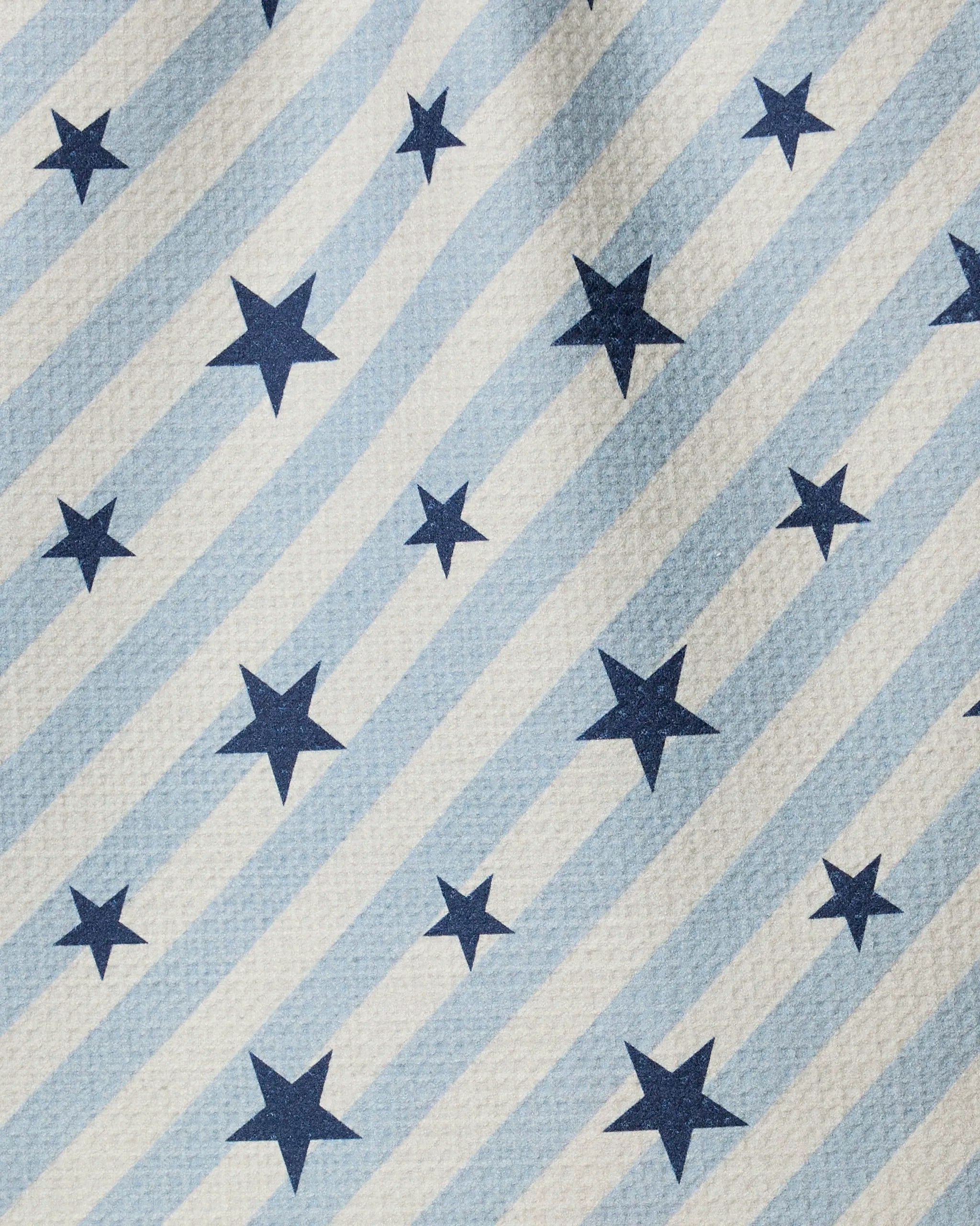 The Geometry "Bright Stars" towel features light blue and white stripes with dark blue stars in various sizes. Its ultra-absorbent, slightly textured material makes it ideal for kitchen or bar use.