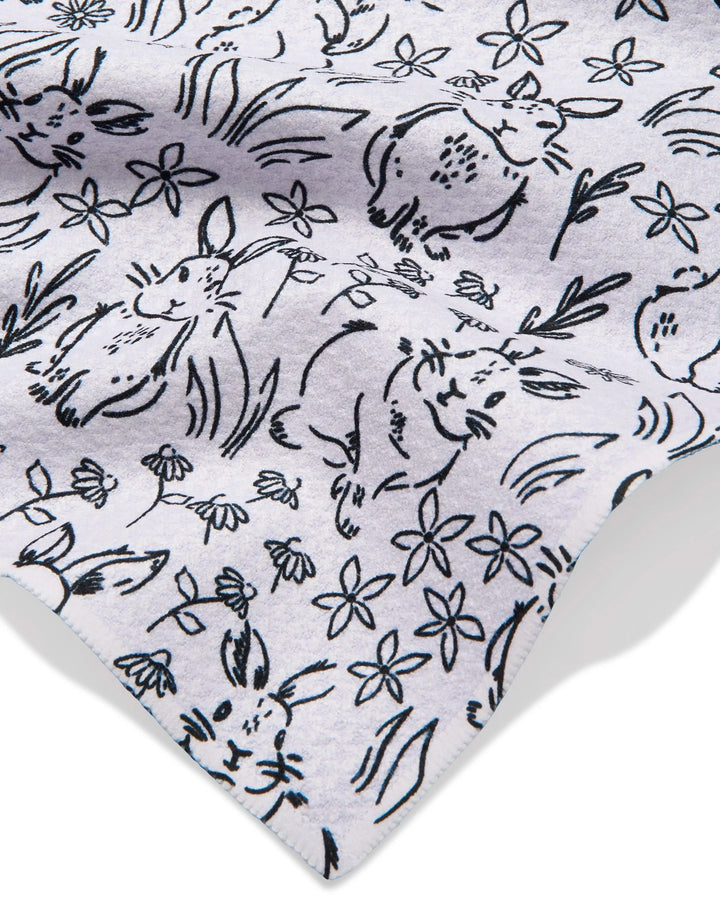 A close-up of Bunny Rabbit Garden by Charlie Rowan Designs shows a playful black line drawing of rabbits, flowers, and grass on a light grey recycled fabric.