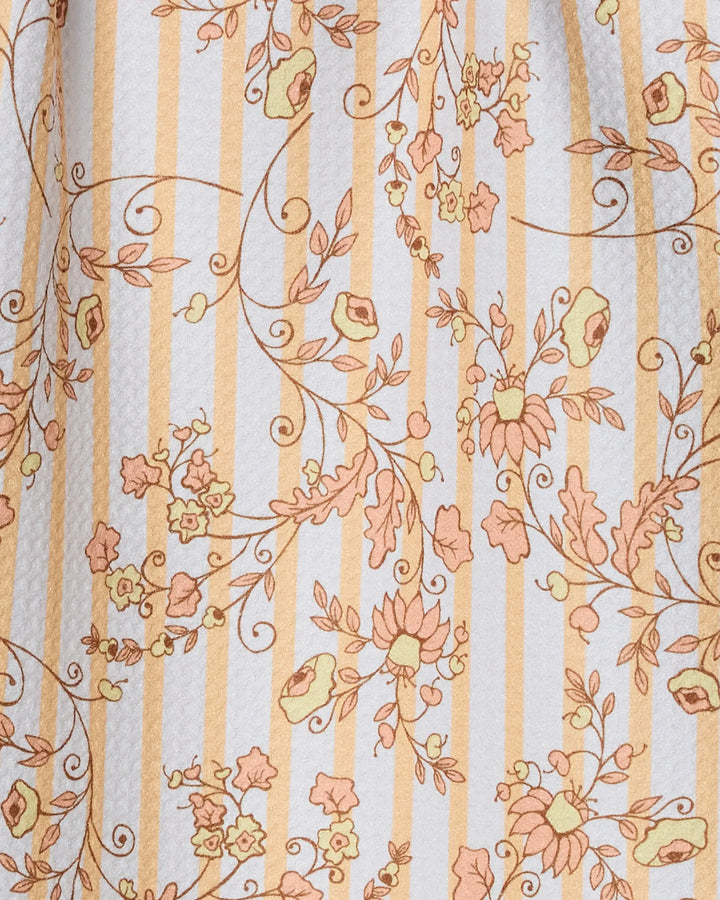 A close-up of Geometry's Buttercup Vine bar towel, crafted from recycled materials and featuring vertical yellow and white stripes adorned with orange and yellow floral vines.